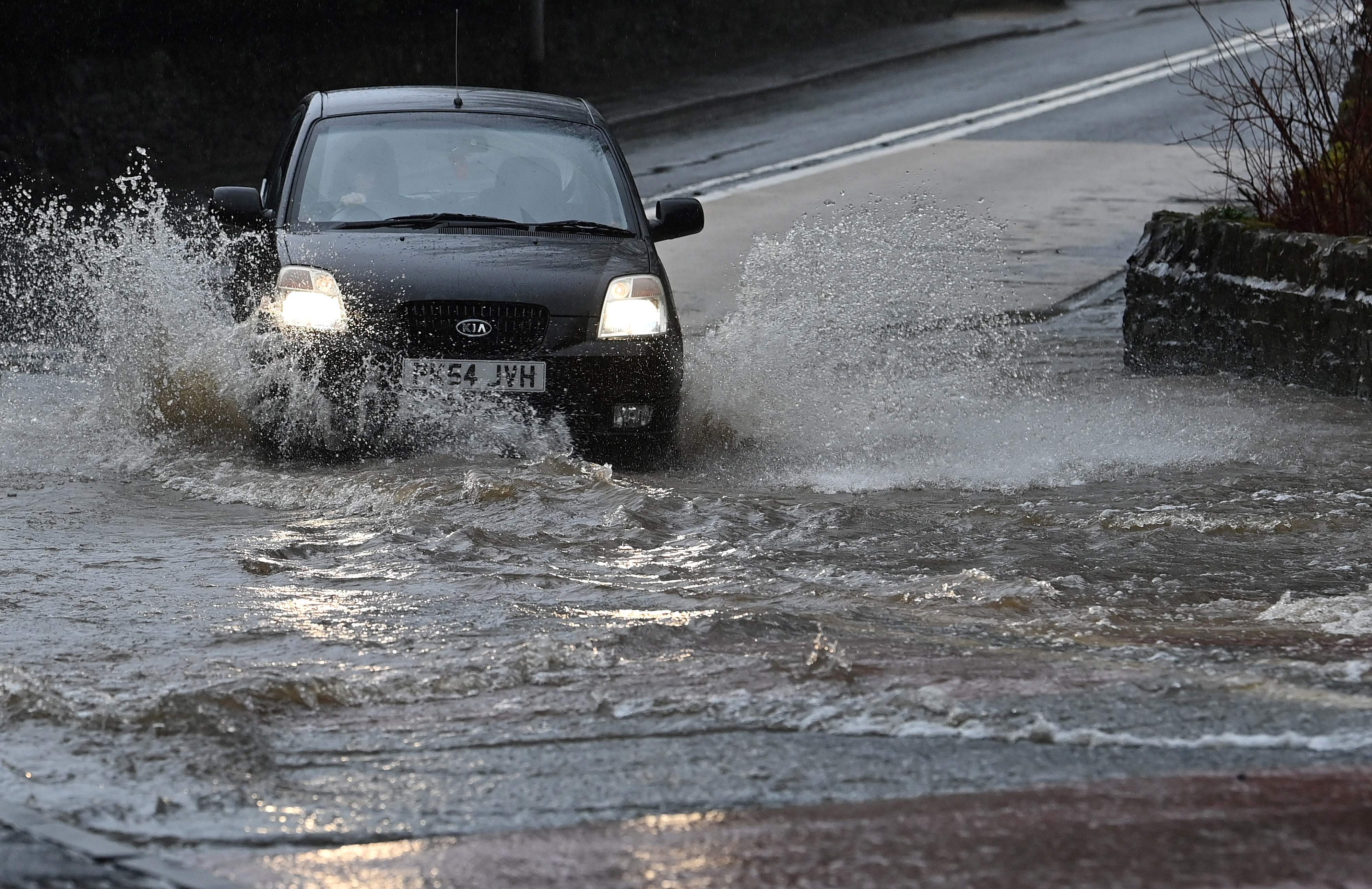 Sebuah mobil melintasi jalan yang tergenang banjir akibat Badai Christoph di Inggris.