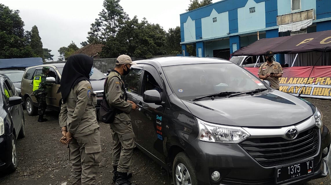 Petugas memeriksa pengendara yang hendak memasuki wilayah Kabupaten Sukabumi, Jawa Barat di perbatasan dengan Cianjur, Selasa (19/1).