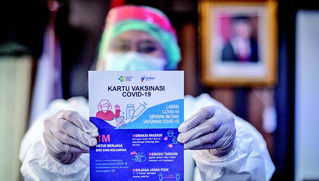 VAKSINASI COVID-19 MULAI DI JAKARTA: Petugas medis menunjukkan kartu vaksinasi covid- 19 sebelum dimulainya penyuntikan vaksin CoronaVac  