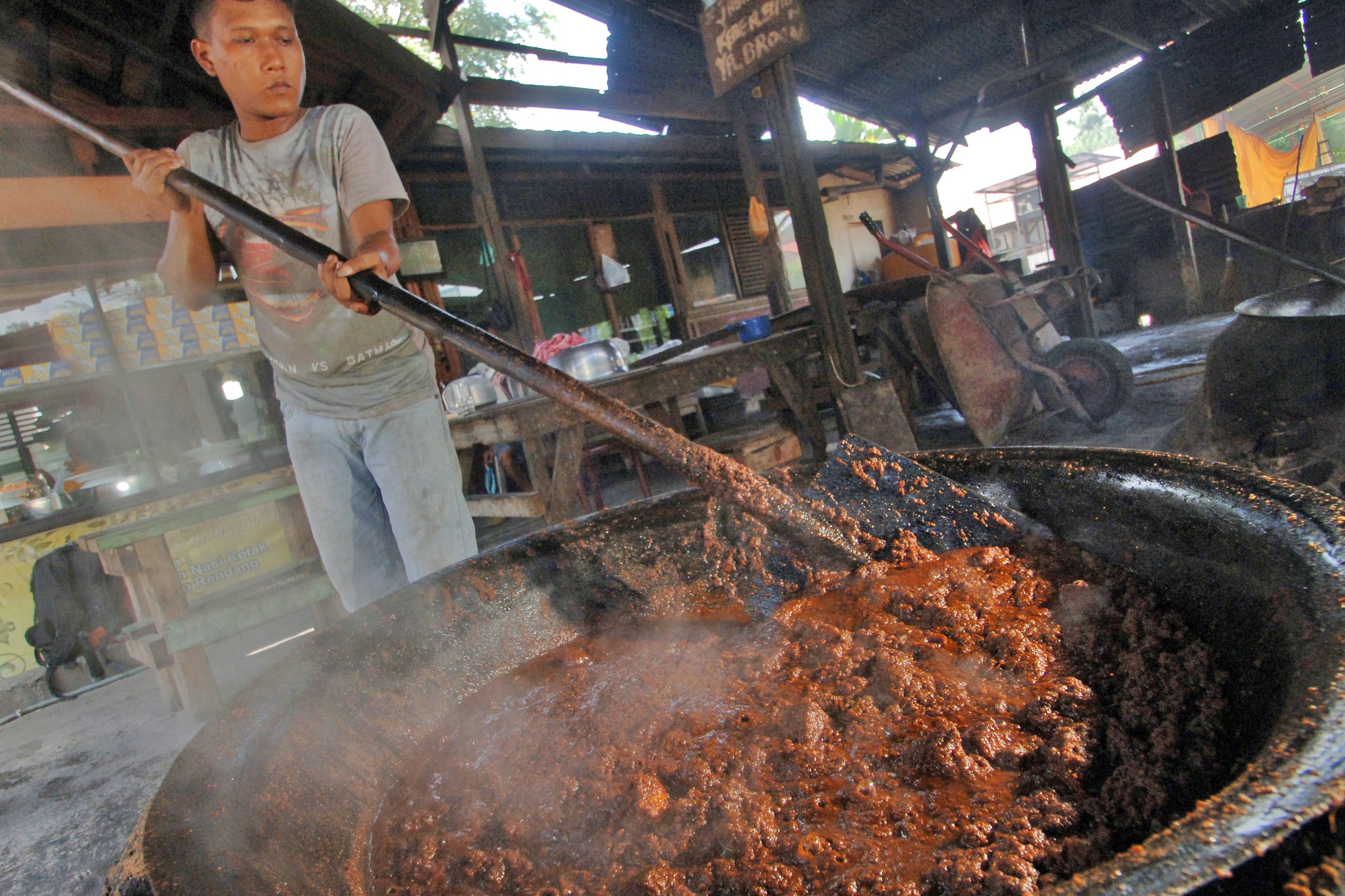 Seorang pekerja mengeringkan rendang daging sapi yang dimasak menggunakan tungku di rumah randang Rajo-rajo, di Padang, Sumbar.