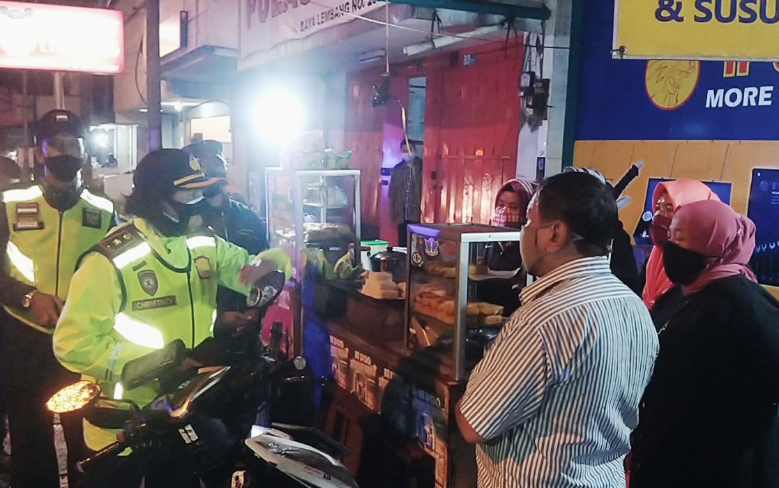 Petugas menyosialisasikan peraturan PPKM kepada pelaku usaha dan masyarakat di Lembang