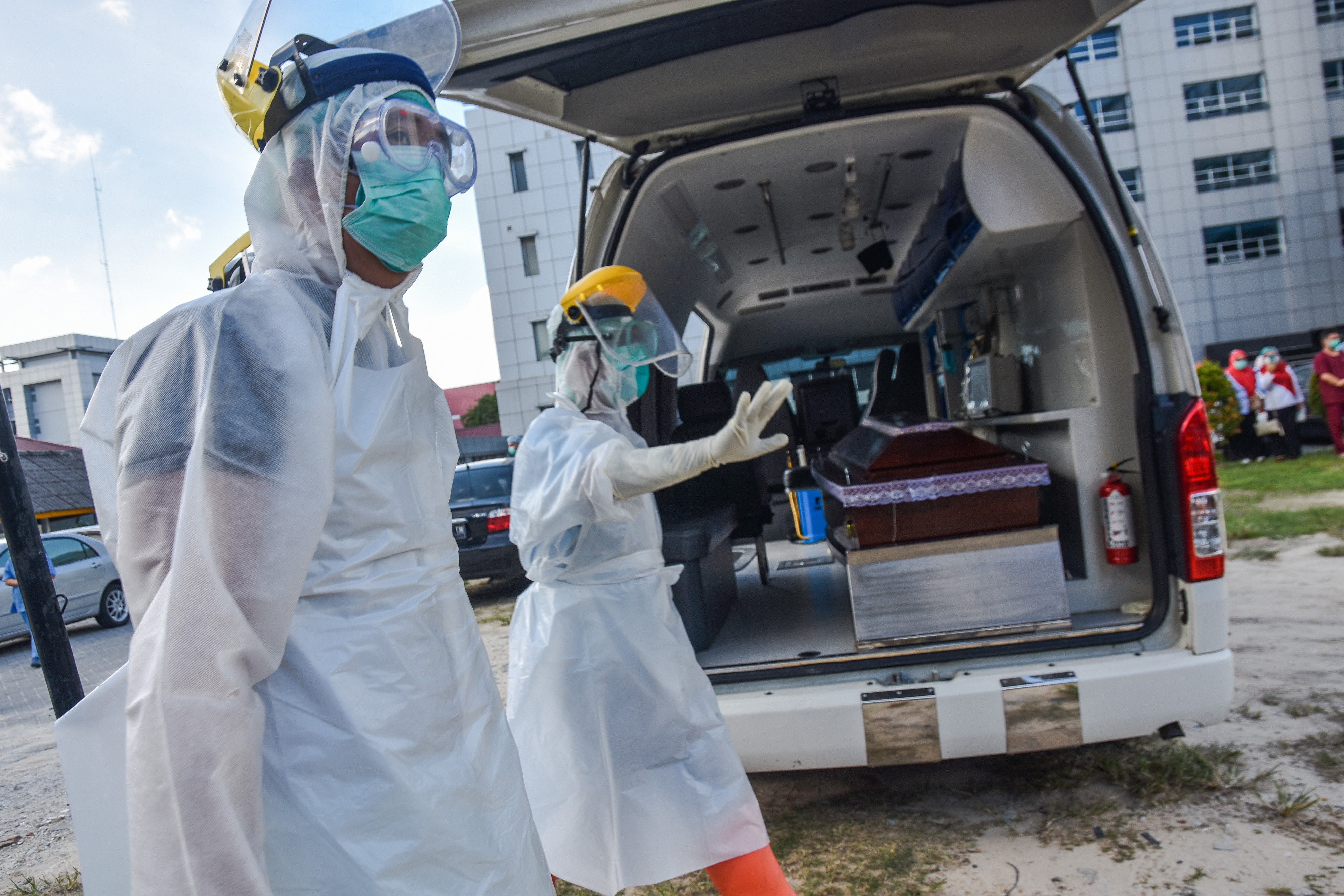 Sejumlah tenaga kesehatan mengenakan alat pelindung diri lengkap untuk memasukan peti mati berisi jenazah