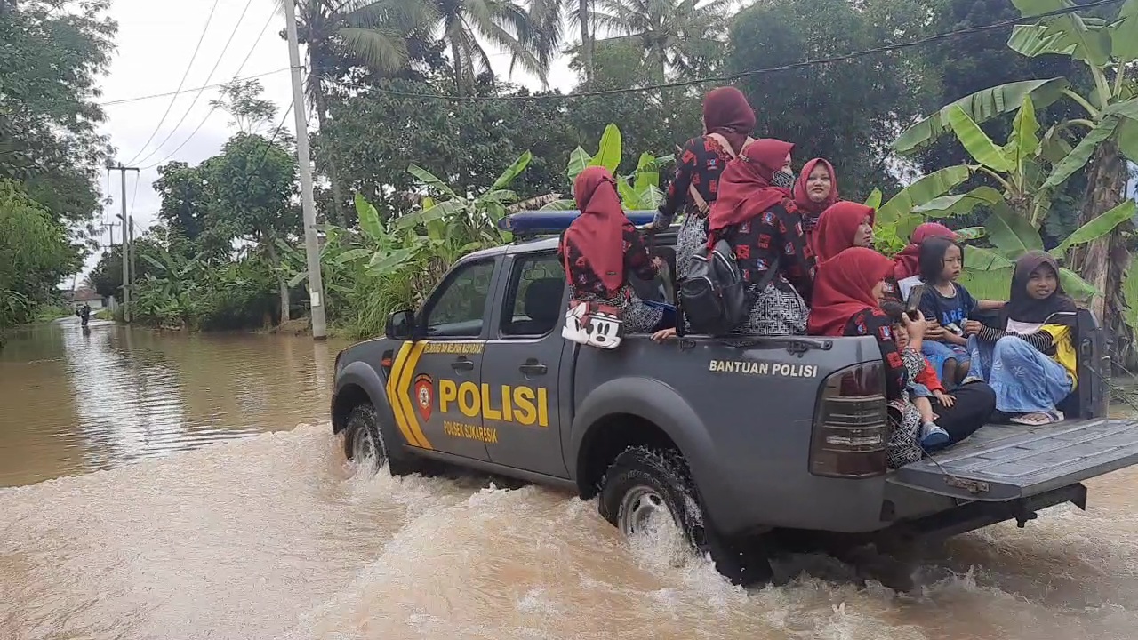 Anggota Polsek Sukaresi membantu warga melintasi genangan banjir akibat luapan Sungai CItanduy dengan mobil patroli. 