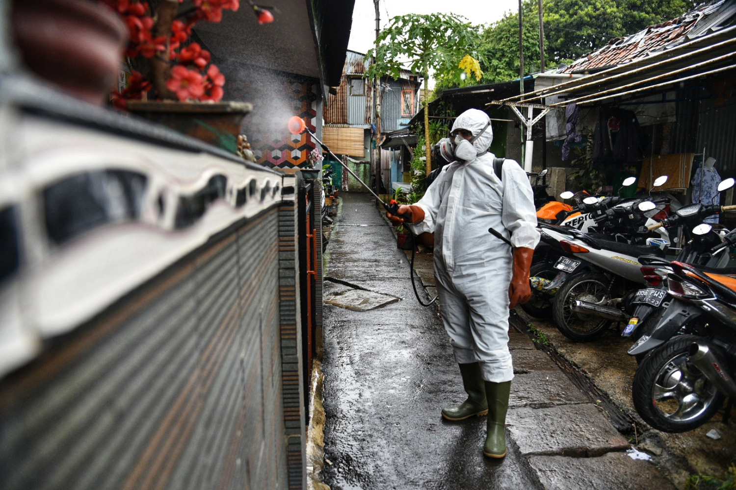 Petugas PMI Kecamatan Menteng menyemprotkan disinfektan di kawasan zona merah di jalan Menteng Tenggulun RW 01, Jakarta Pusat.