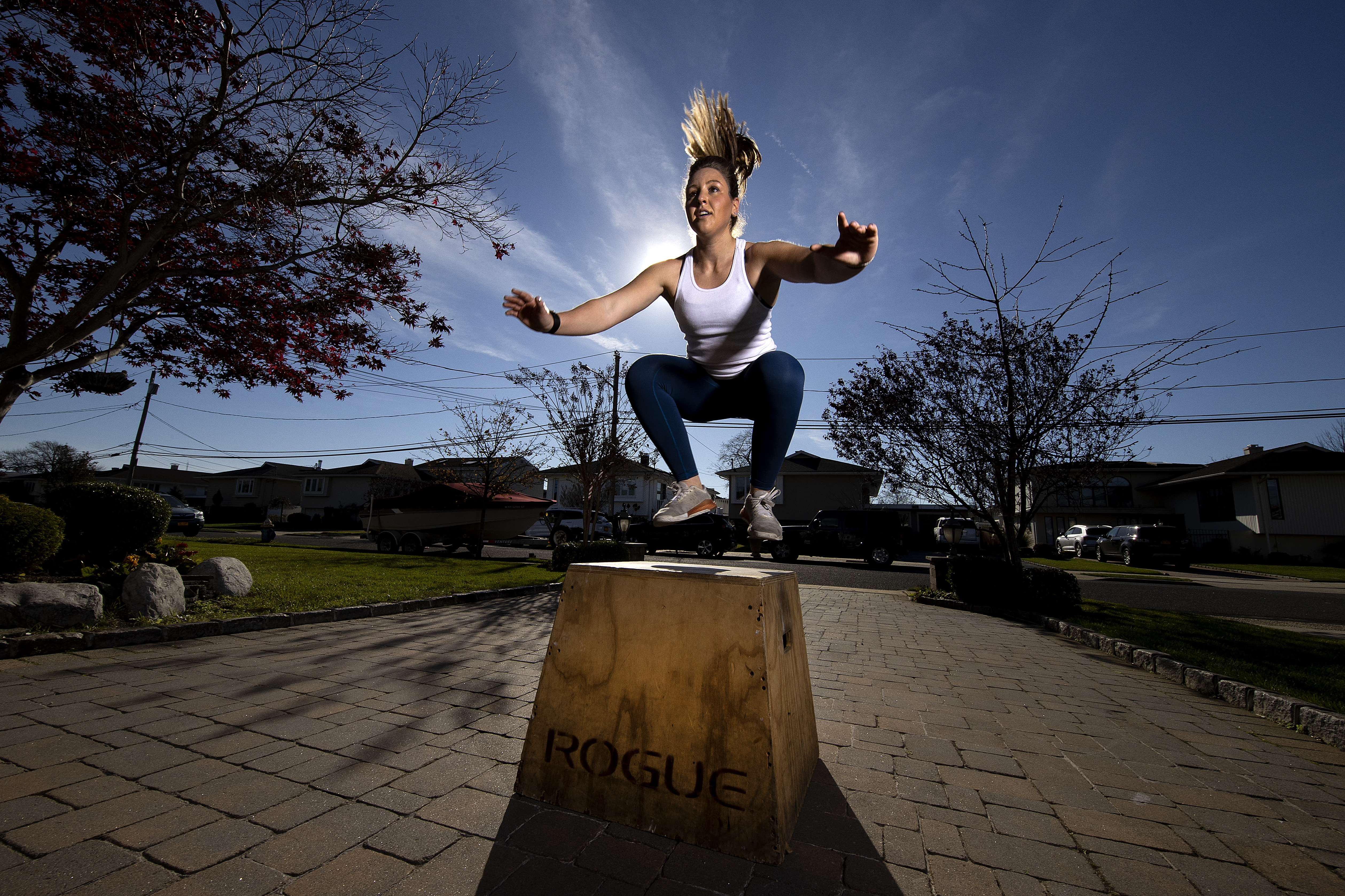 Alexa Hoovis berolahraga di halaman rumah dengan pelatih kebugaran virtualnya Dennis Guerrero di Oceanside, New York, beberapa waktu lalu.