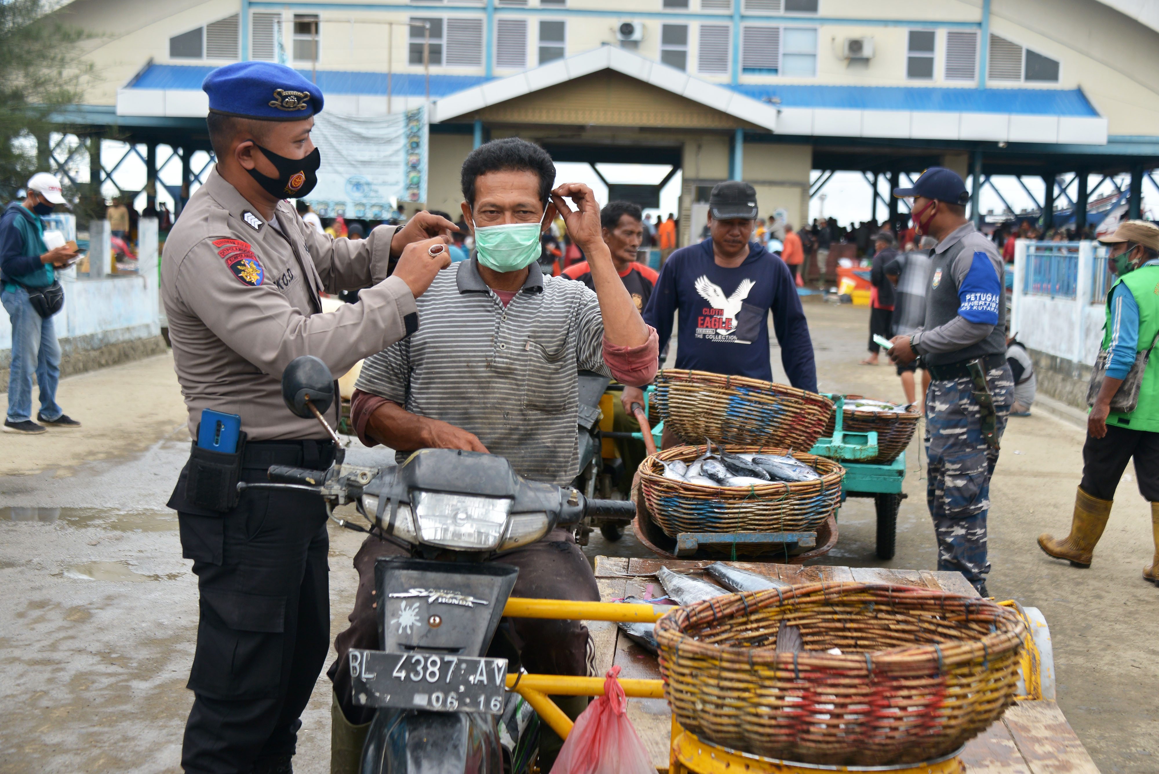 Anggota Polairud membagikan masker kepada nelayan dan pedagang keliling di pusat pelelangkan ikan di Aceh, Selasa (24/11/2020).