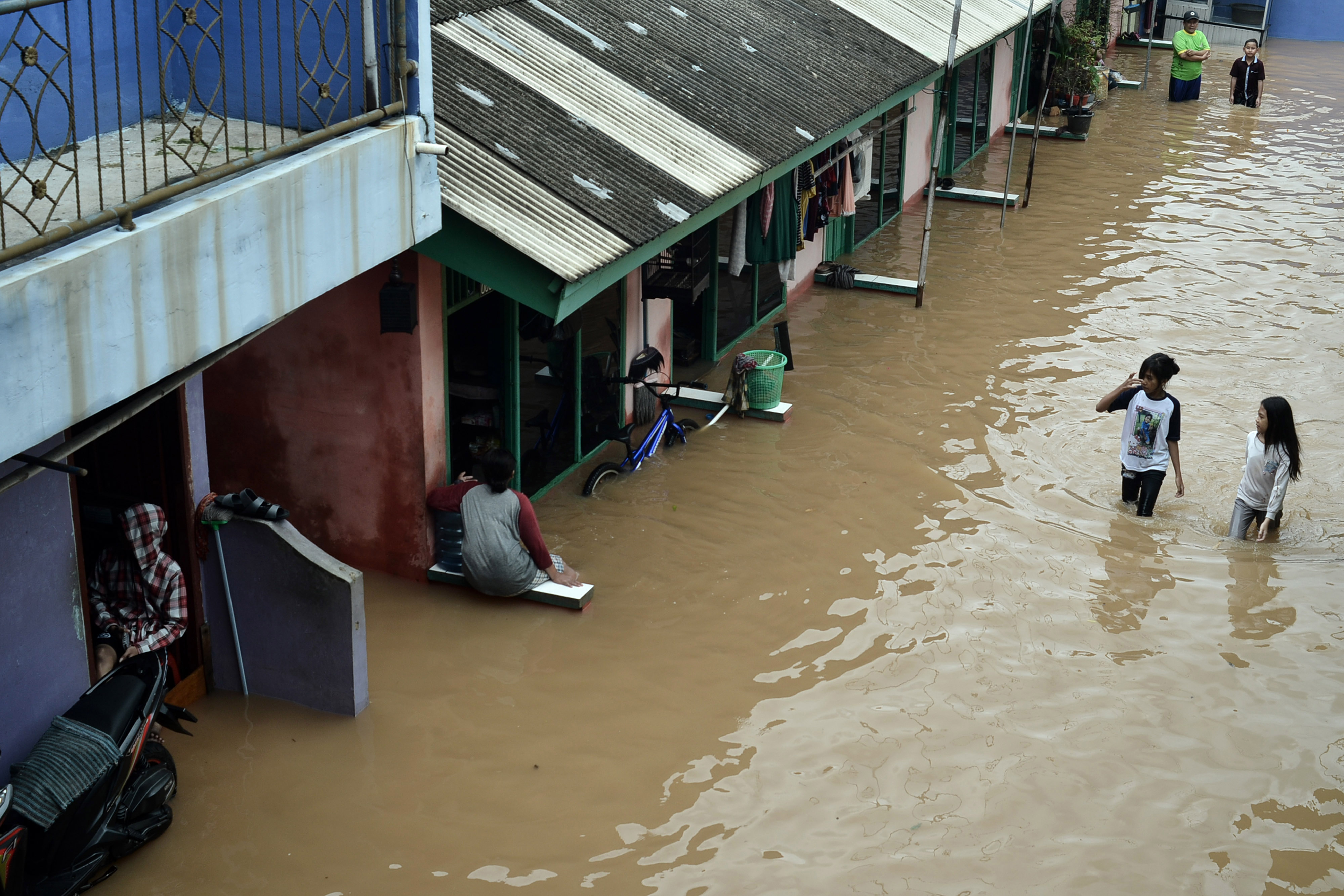 Warga melintasi di depan rumahnya yang terendam banjir di Cibitung, Kabupaten Bekasi, Sabtu (20/2/2021).