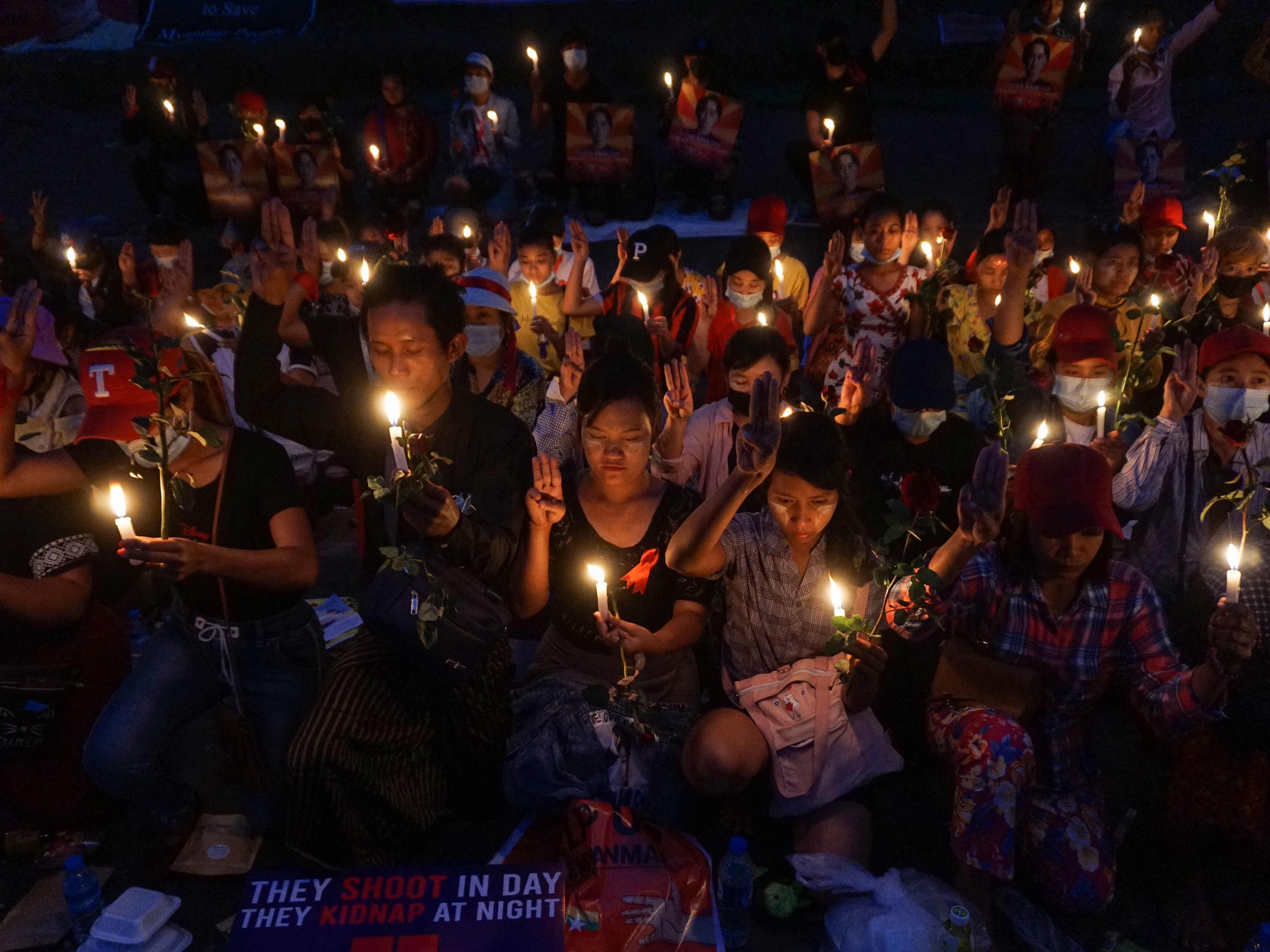 Para pengunjuk rasa mengadakan nyala lilin di luar Kedutaan Besar AS selama demonstrasi menentang kudeta militer di Yangon, Minggu (21/2).