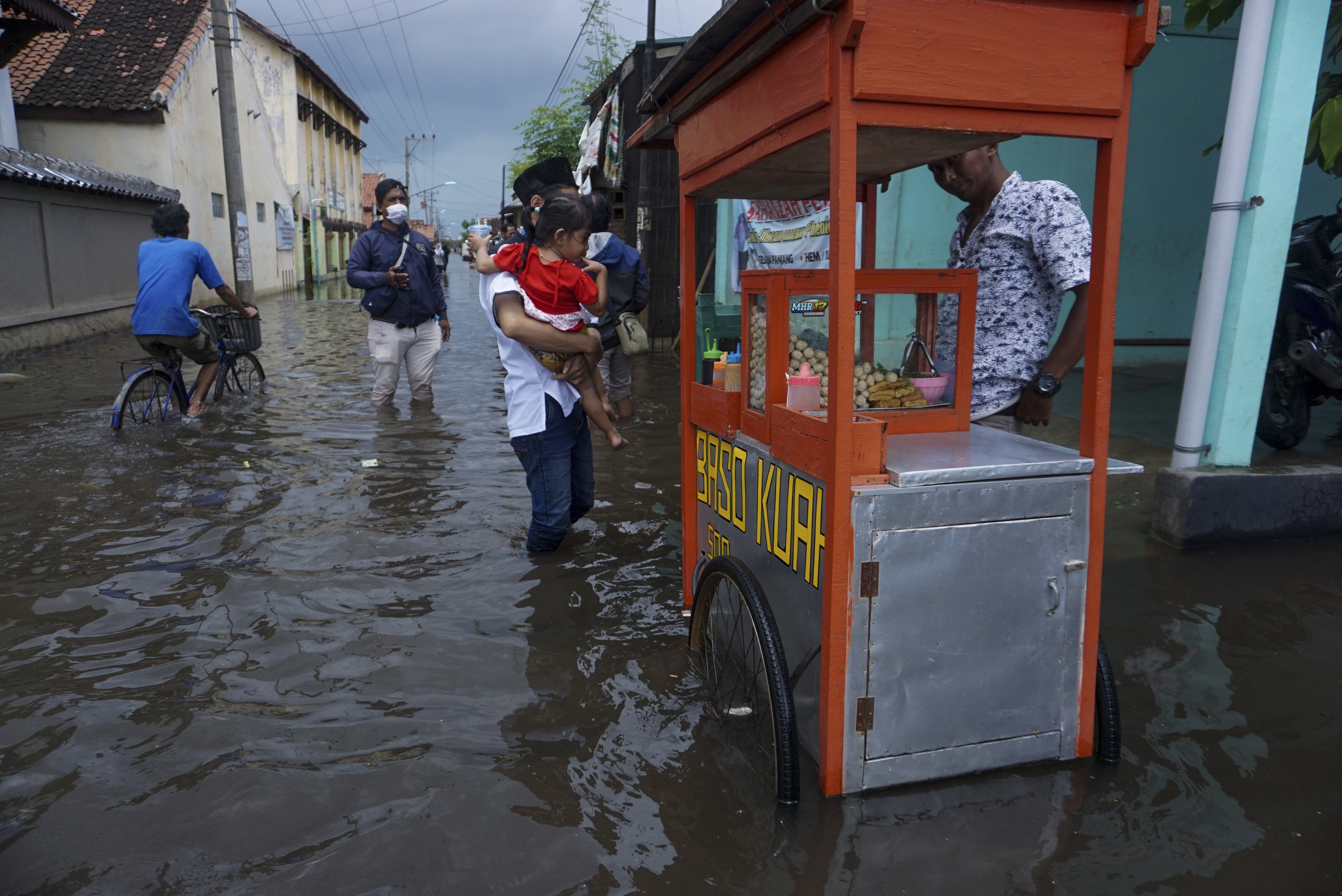 Warga membeli bakso di depan rumahnya yang tergenang banjir di Pekalongan, Jawa Tengah, Kamis (4/2/2021)