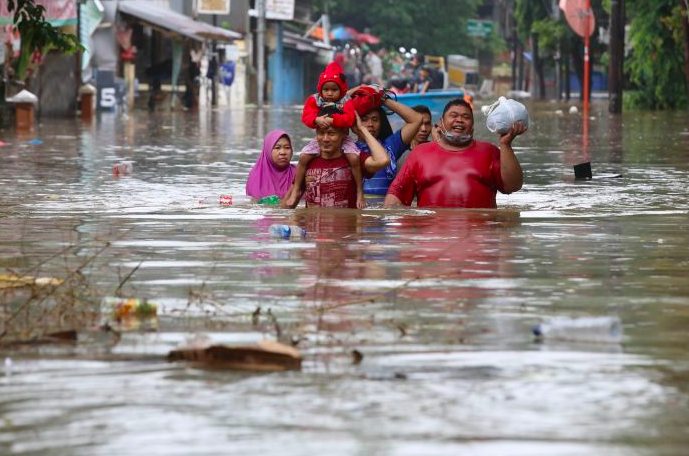 Warga menyelamatkan diri saat banjir melanda kawasan Bendungan Hilir, Jakarta.