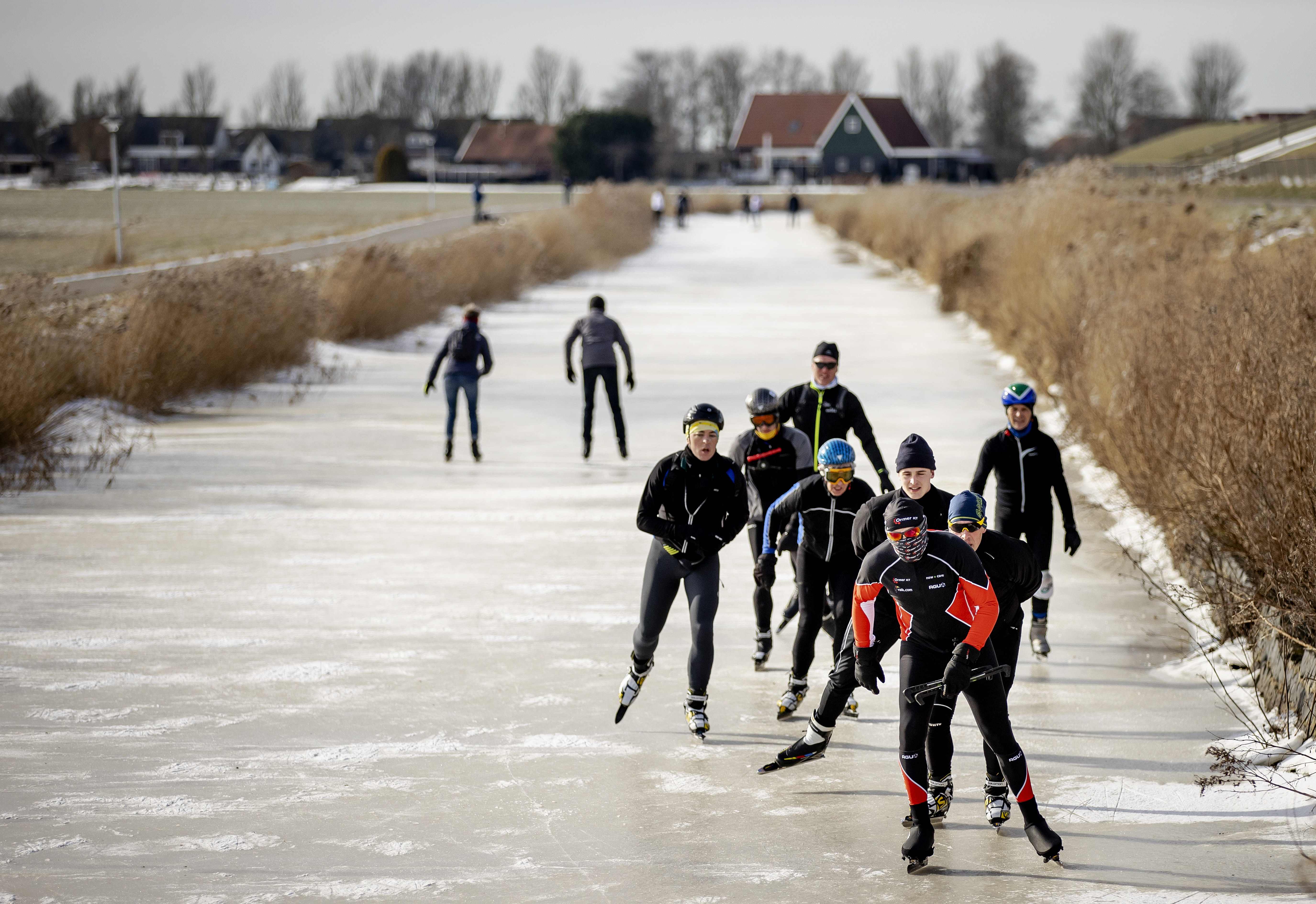 Warga meluncur di sebuah kanal yang membeku di Hindeloopen, Belanda, Minggu (14/2)