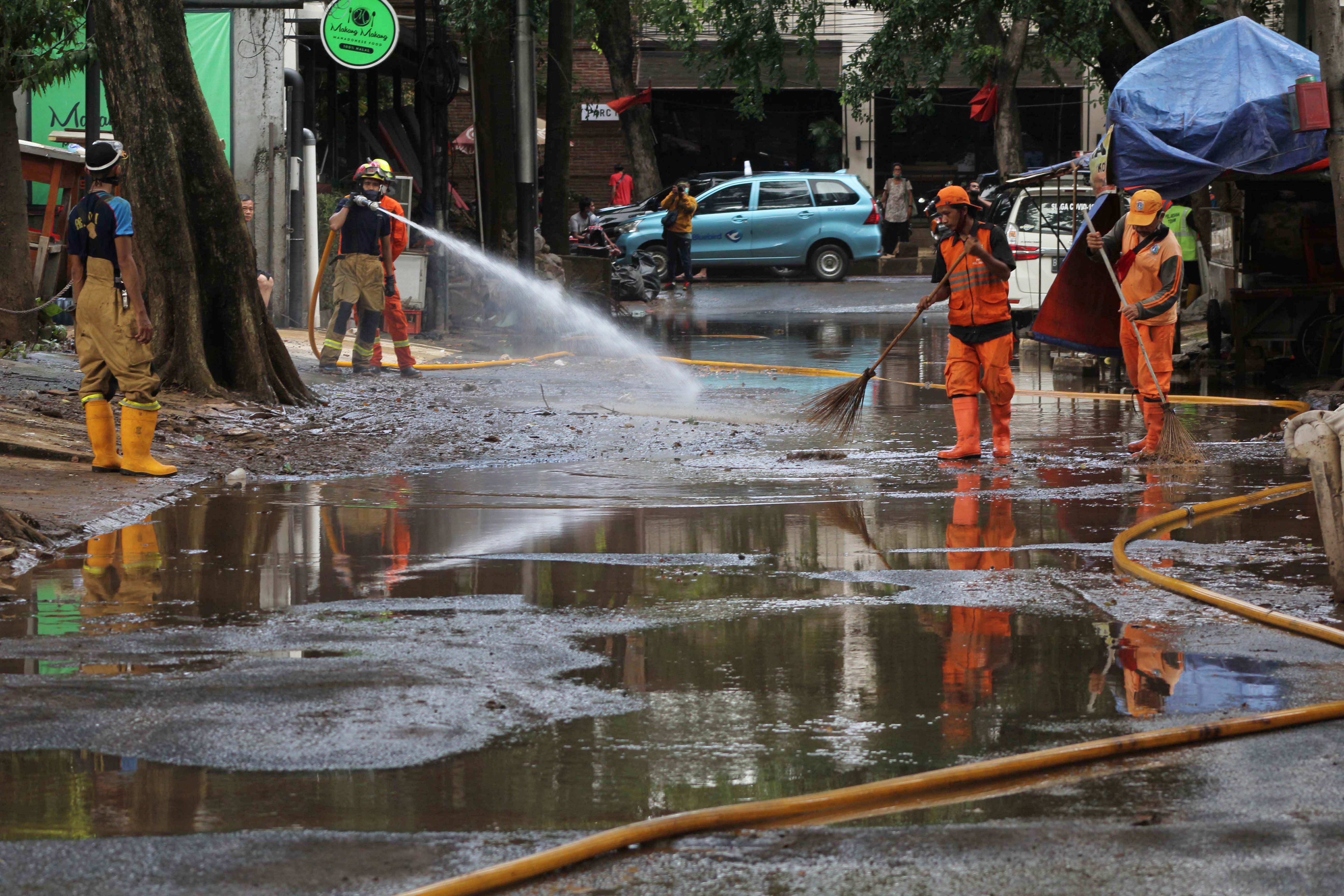 Petugas Pemadam Kebakaran dan PPSU memberihkan lumpur-lumpur sisa dari banjir di Kemang, Jakarta Selatan, Minggu (22/2/2021).