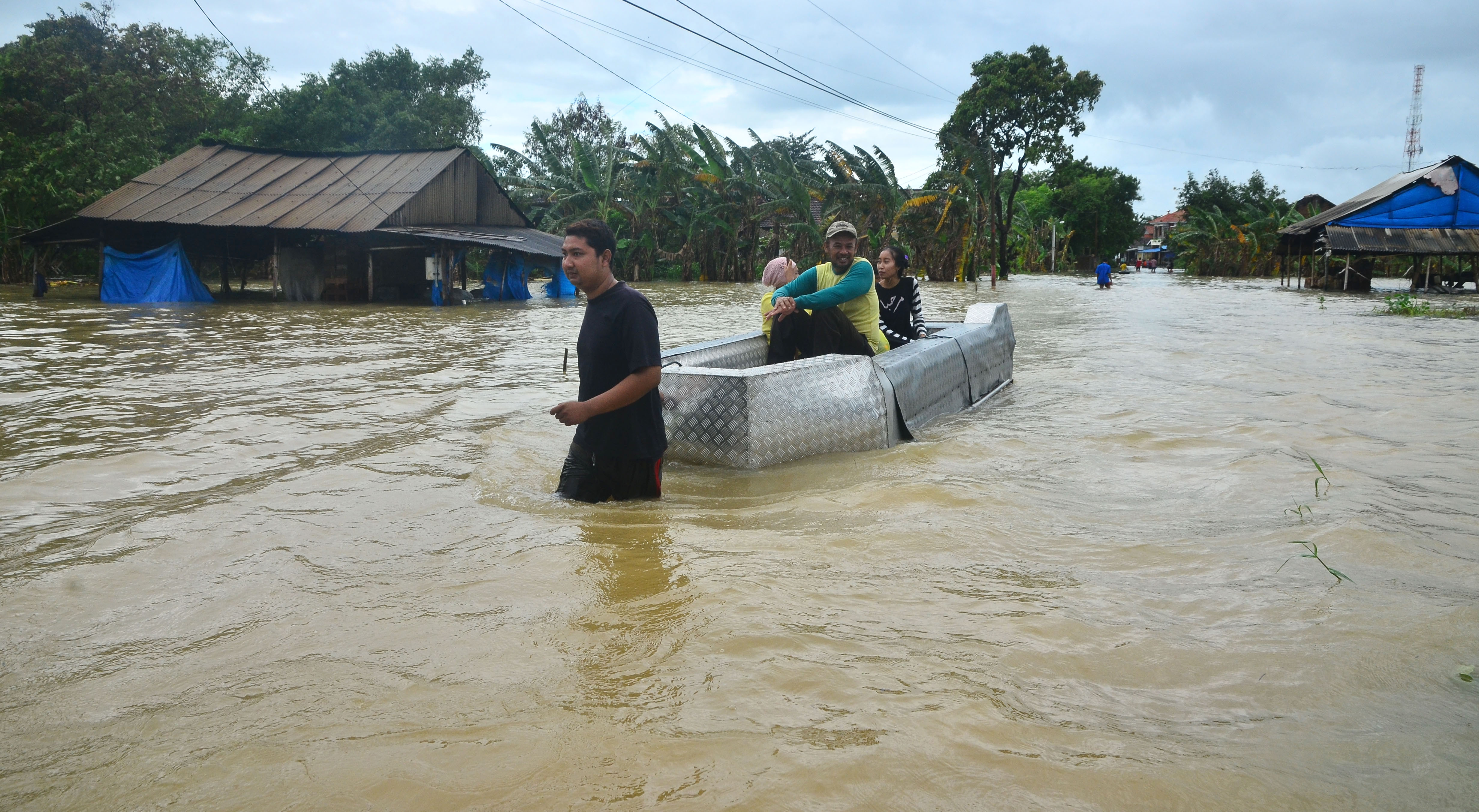 Warga menggunakan perahu melintasi jalan yang terendam banjir di Desa Kedungdowo, Kudus, Jawa Tengah, Selasa (2/2).
