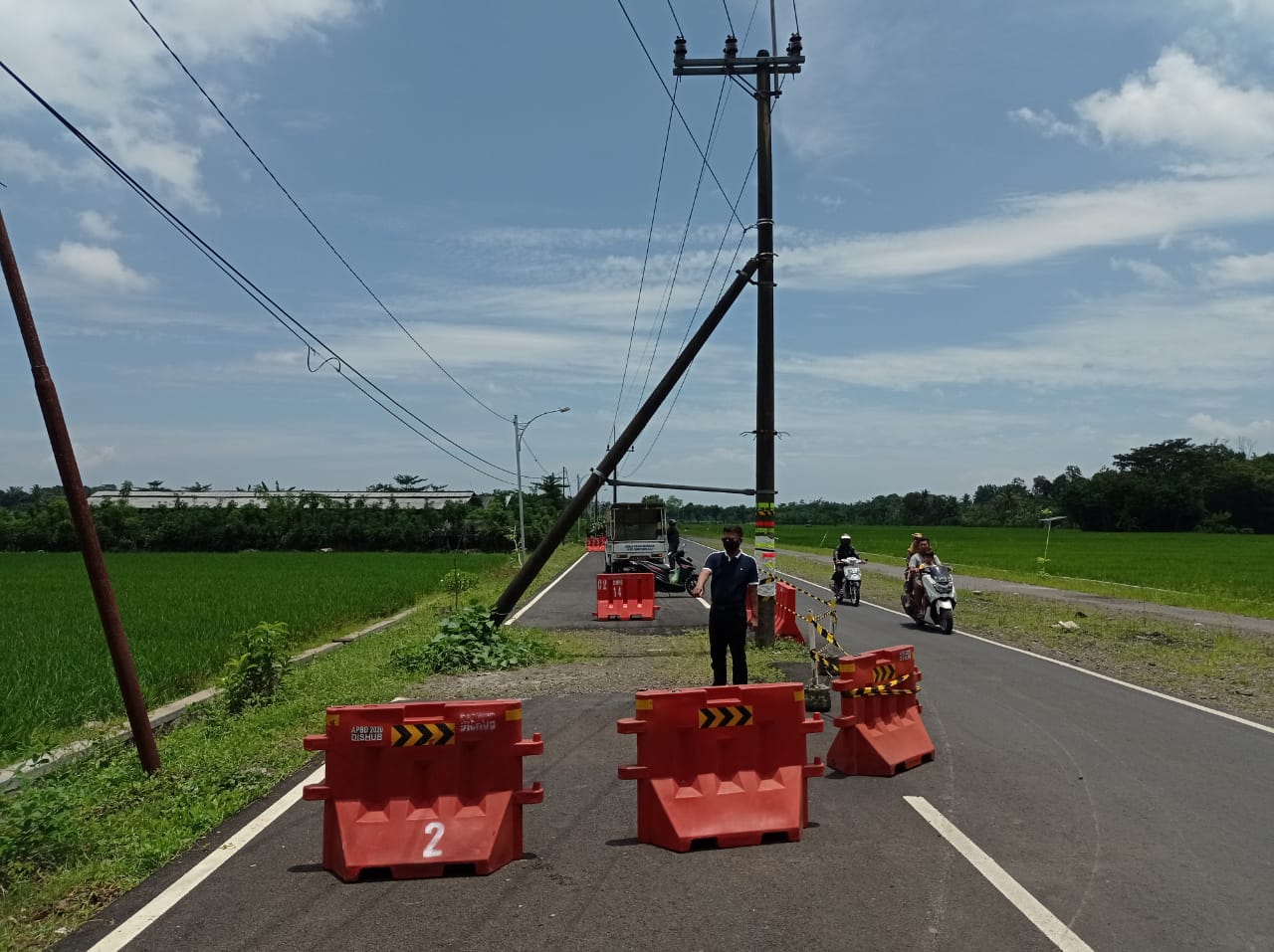 Petugas memasang rambu adanya tiang listrik berada di tengah jalan raya jurusan Dasri, Kecamatan Tegalsari, Kabupaten Banyuwangi, Jatim.