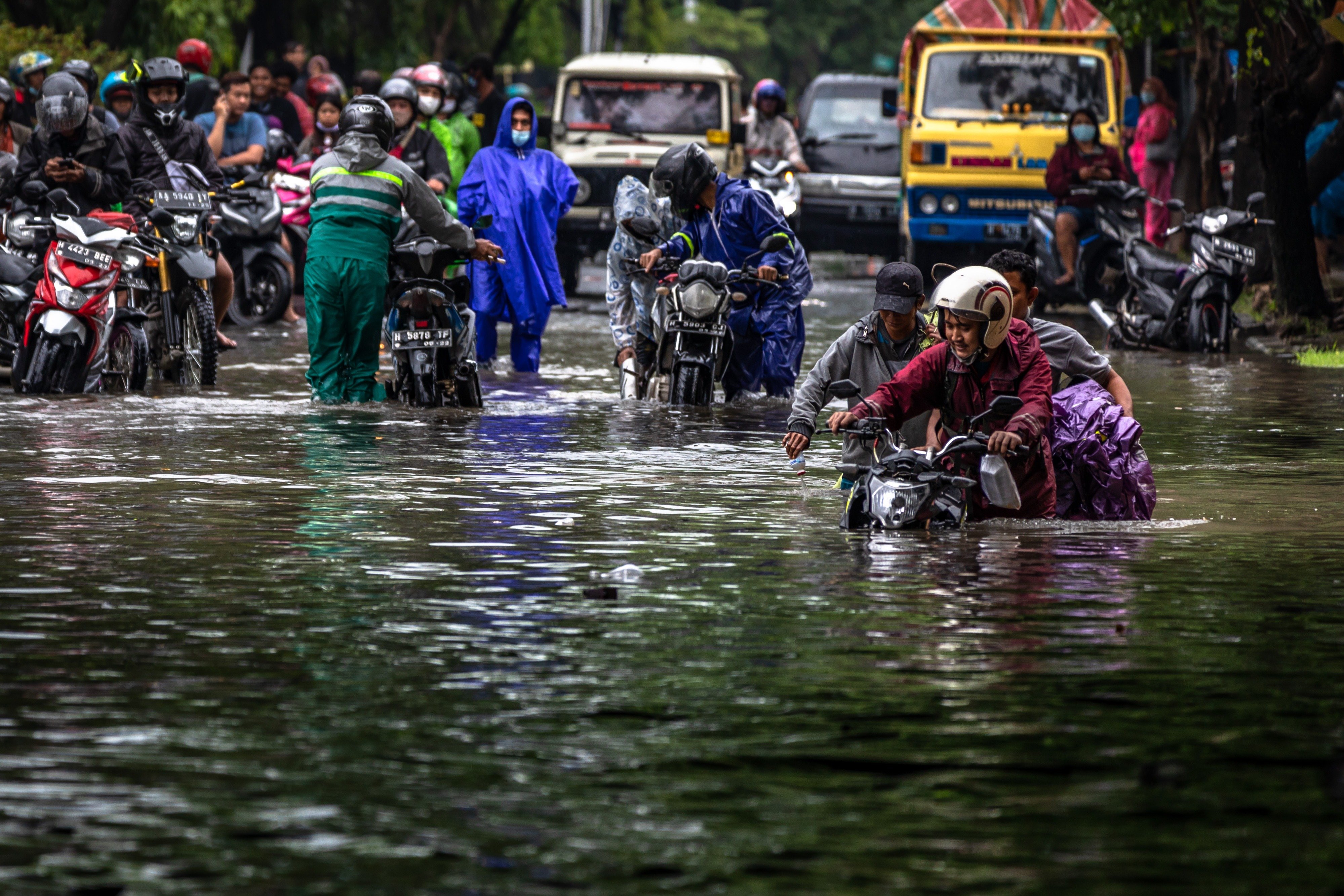 Warga mendorong sepeda motornya yang mogok dengan mengarungi banjir di Jalan Raya Arteri Soekarno-Hatta, Semarang, Jateng, Sabtu (6/2).