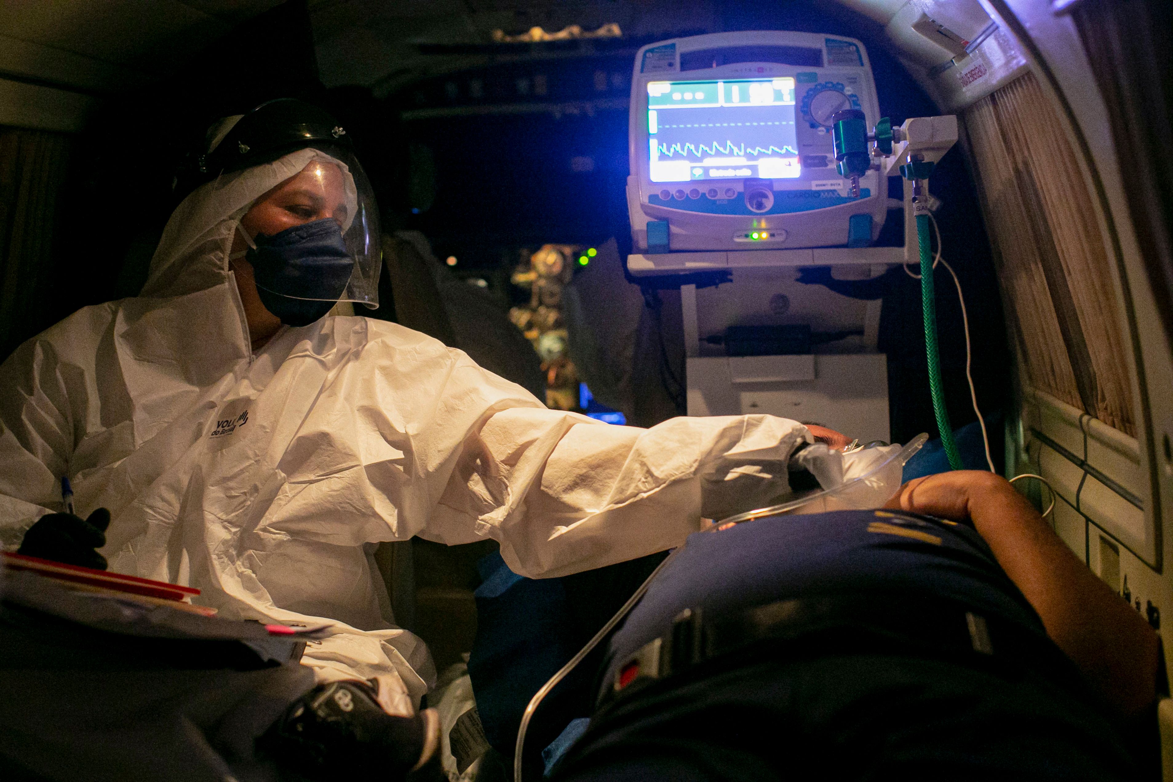 Petugas kesehatan memeriksa kondisi seorang pasien covid-19 yang akan diterbangkan dari Belterra ke Itaituba, Brasil.