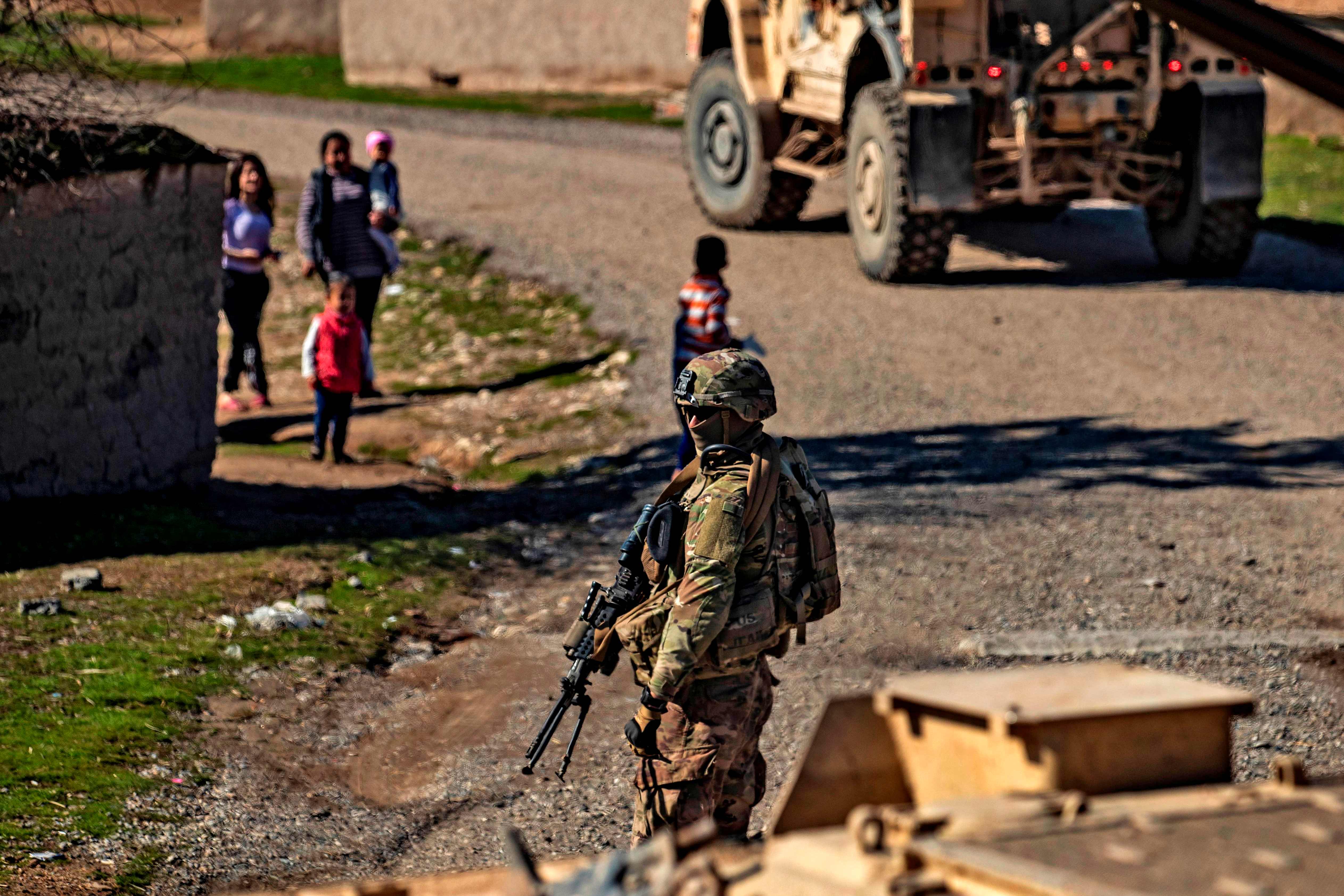 Anak-anak bermain di dekat seorang tentara AS selama patroli di perdesaan dekat al-Malikiyah di timur laut Hasakah, Suriah, Selasa (2/2).