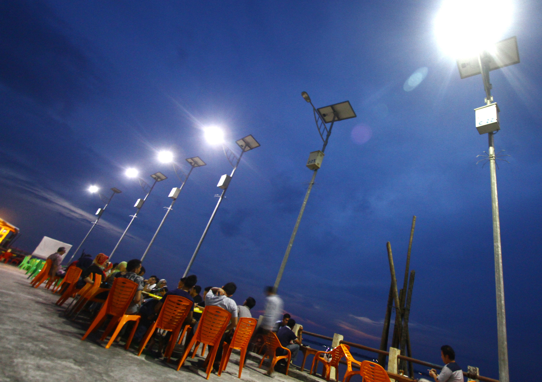 Warga menikmati senja di bawah sinar lampu penerangan jalan umum tenaga surya (PJUTS) di Selatpanjang, Kabupaten Kepulauan Meranti, Riau.