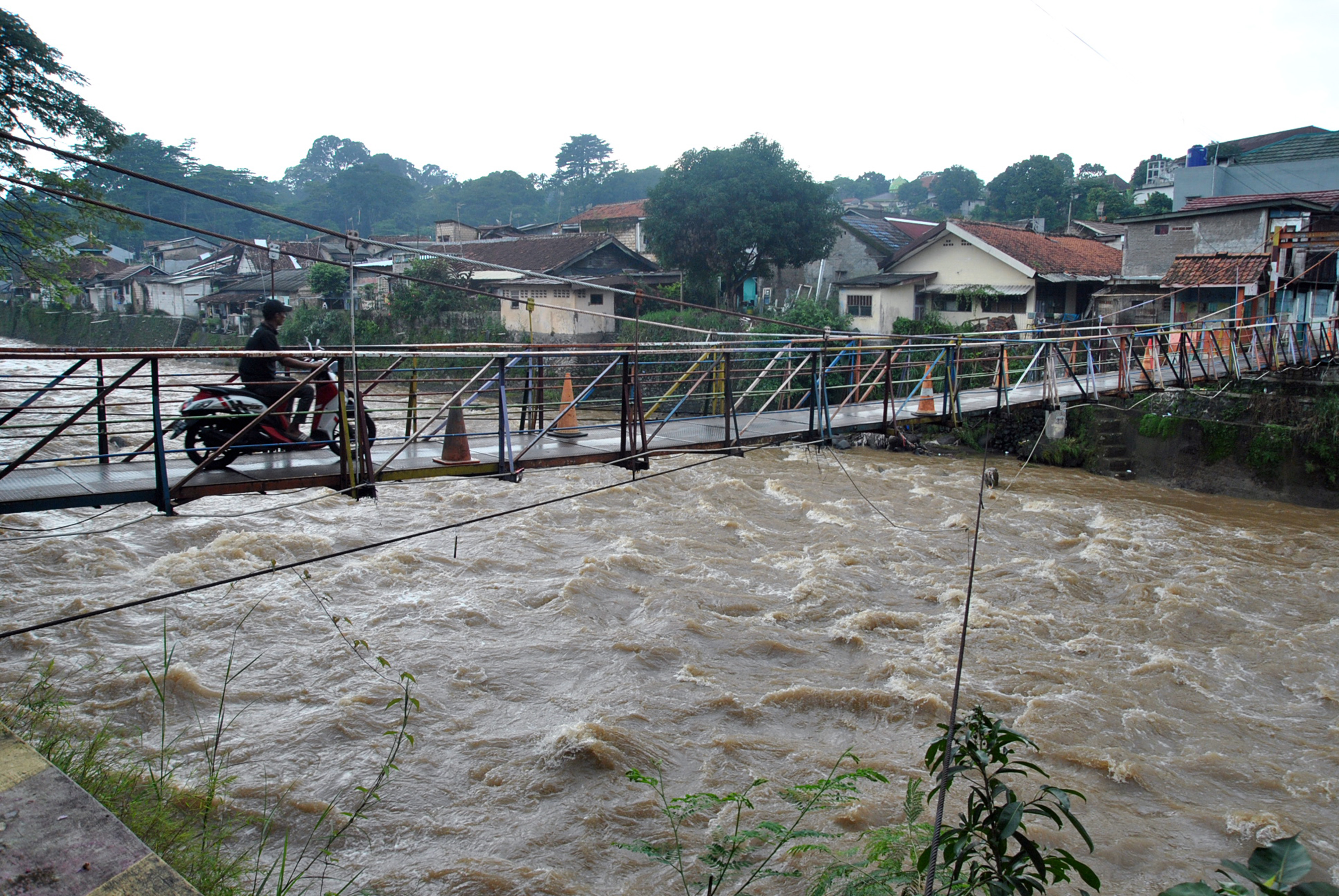 Pengendara motor melintasi jembatan Sungai Ciliwung di wilayah Bogor.