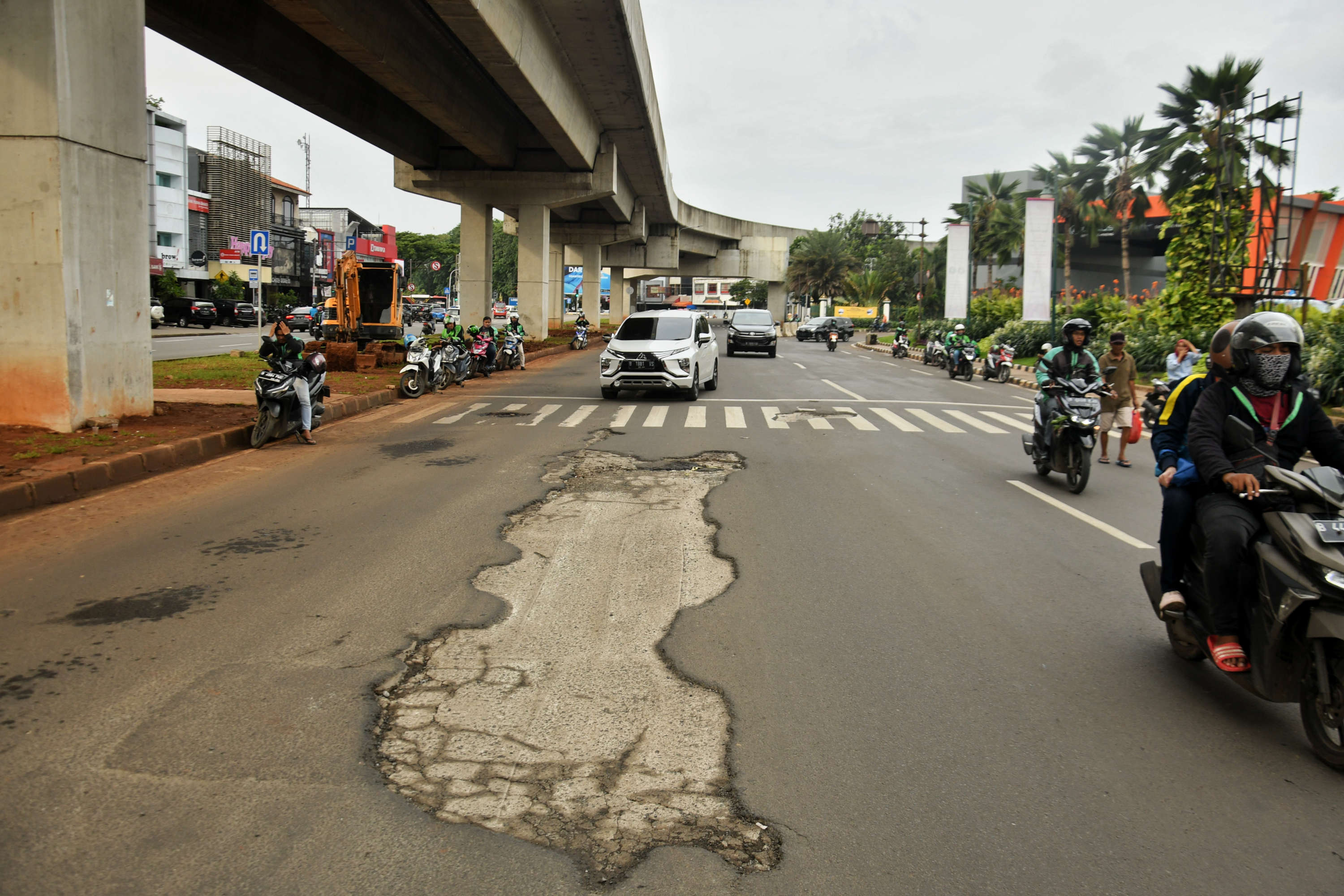 Sejumlah kendaraan memperlambat laju kendaraannya untuk menghindari lubang di kawasan Kelapa Gading, Jakarta, Minggu (1/3/2020)