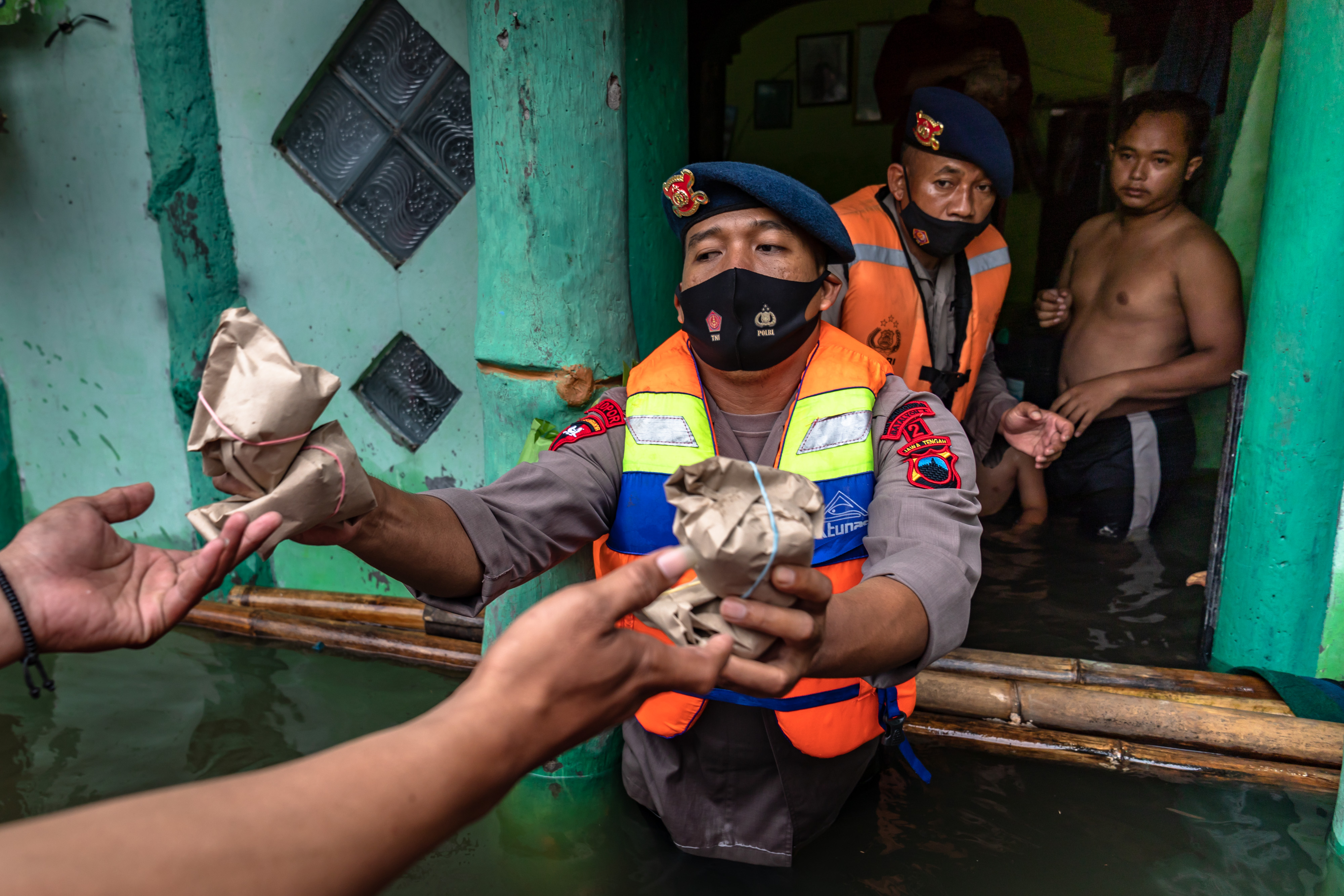 Anggota Polri menyalurkan logistik kepada korban banjir.