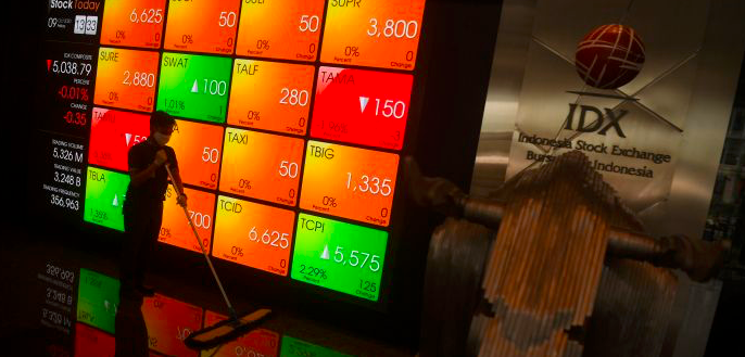 Pekerja melintas di dekat layar digital pergerakan saham di Gedung BEI, Jakarta, Jumat (9/10/2020).