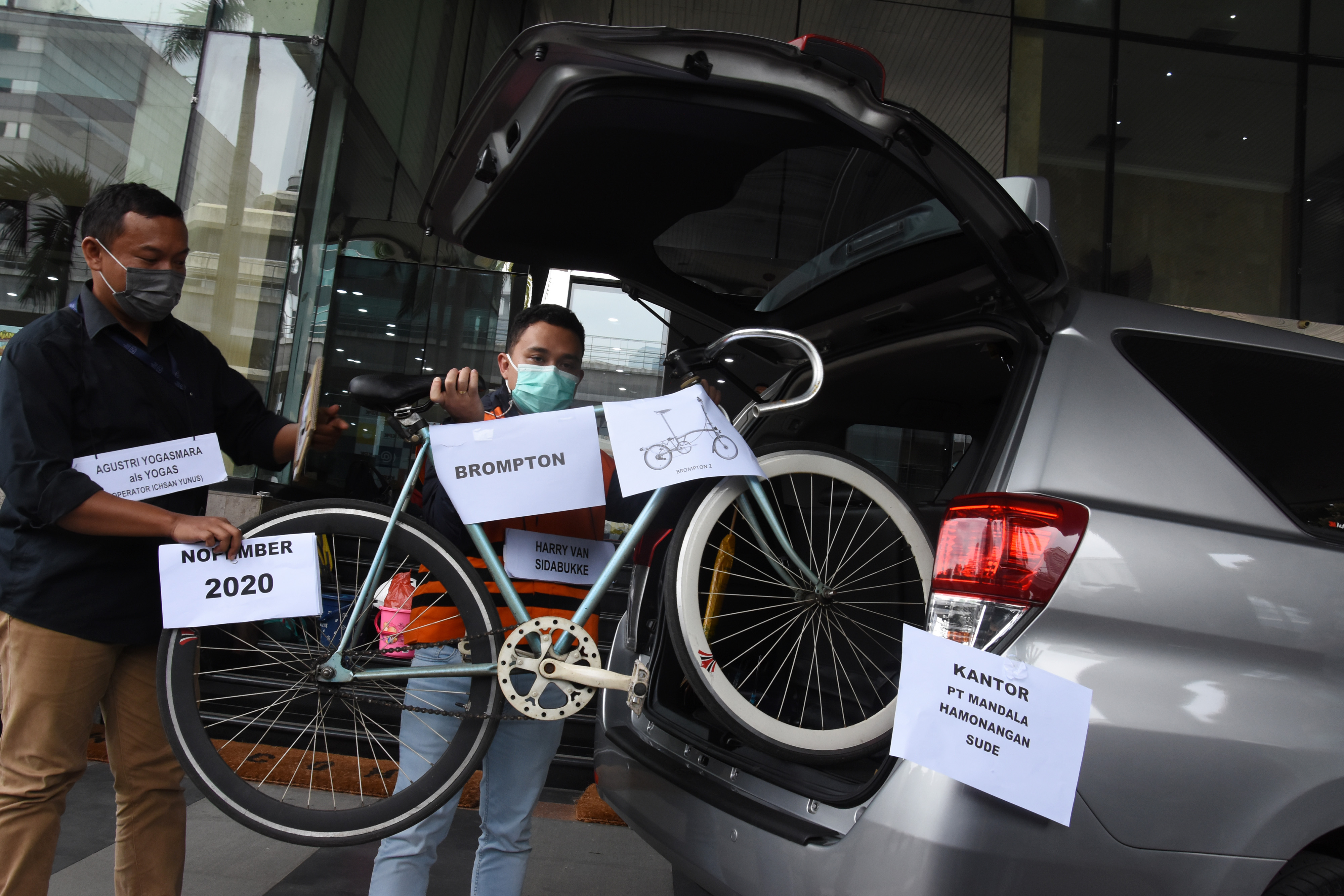 Tersangka dari pihak swasta Harry Sidabuke (kanan) menyerahkan sepeda brompton kepada operator Ichsan Yunus, Agustri Yogasmara.