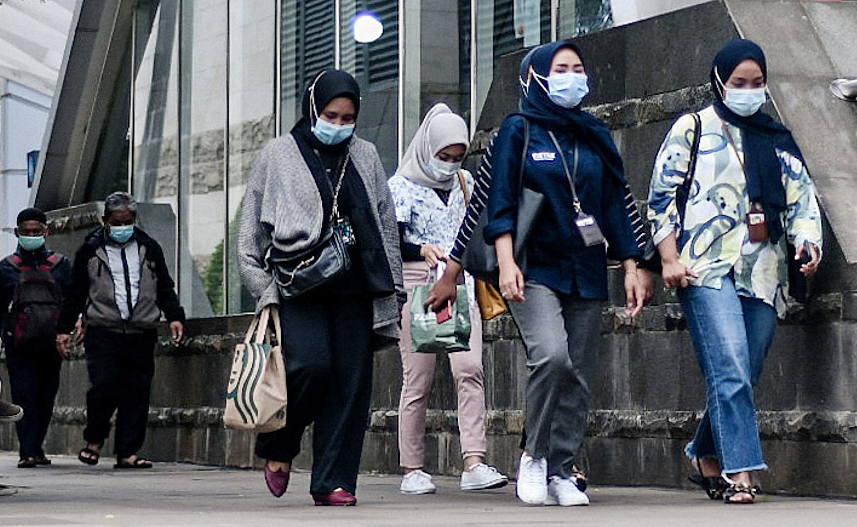 Pekerja berjalan di kawasan perkantoran Jakarta di tengah kebijakan PPKM.