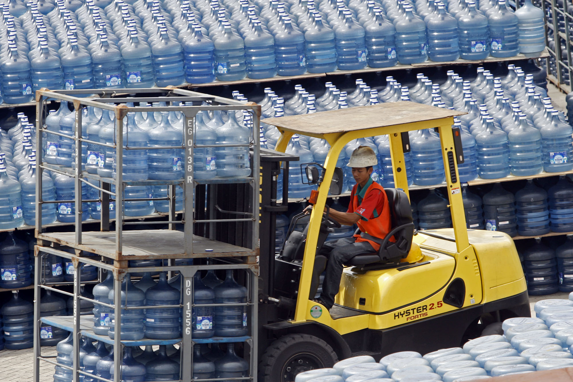 Pekerja tengah mengatur tumpukan galon air minum isi ulang di Jakarta.
