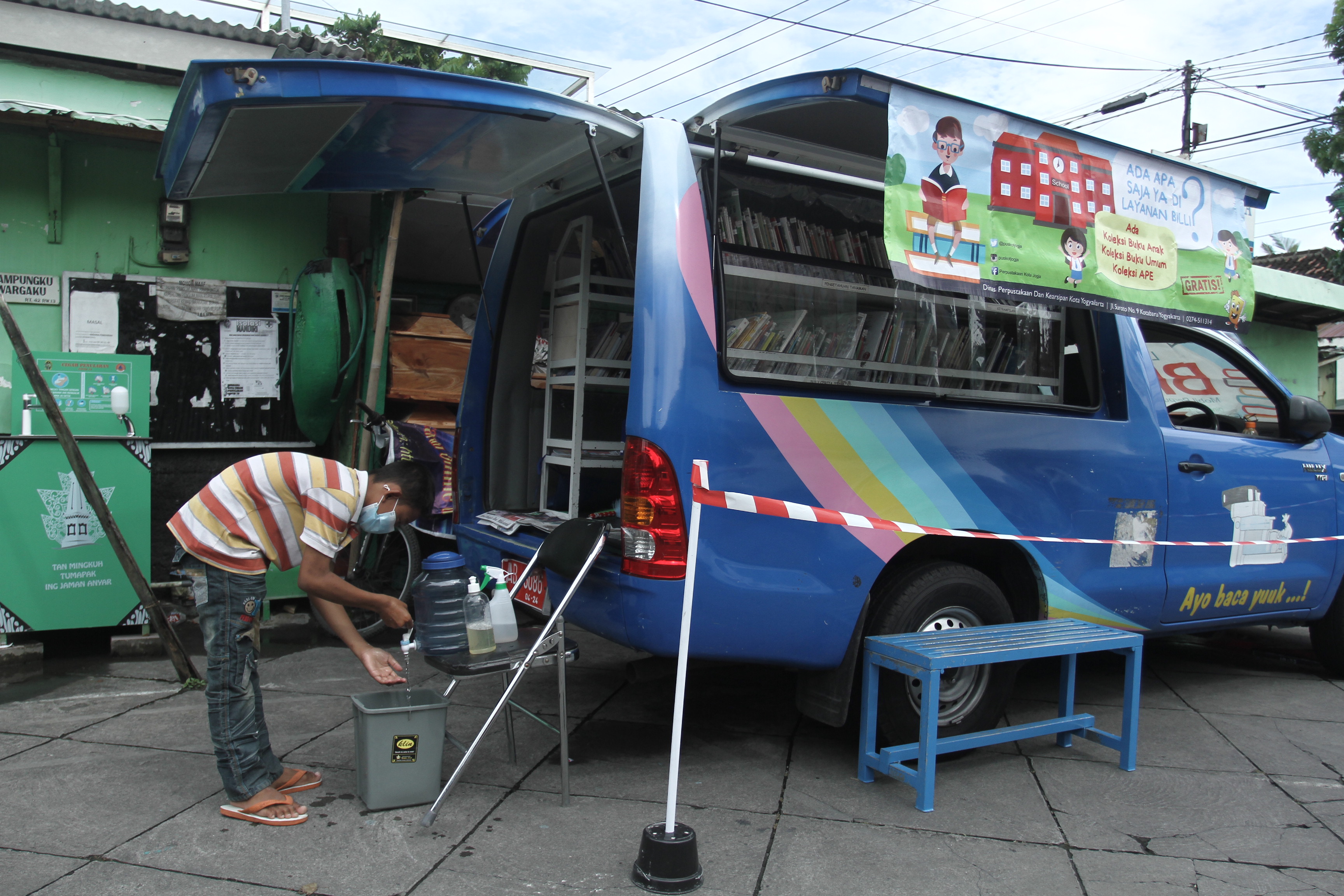 Seorang anak mencuci tangan sebelum meminjam buku di Mobil Perpustakaan Keliling, Prawirodirjan, Gondomanan, Yogyakarta, Rabu (10/2/2021).