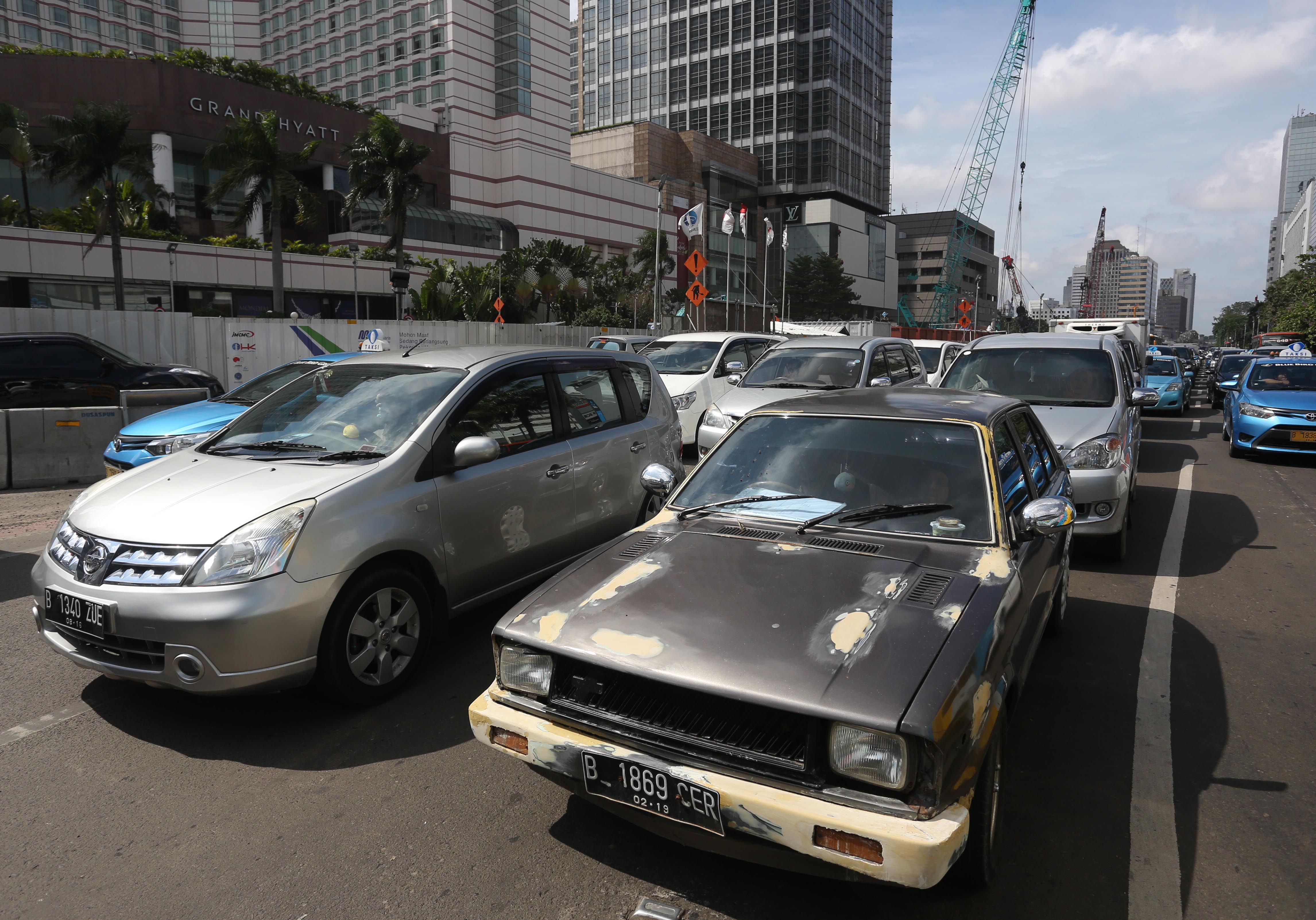 Sebuah mobil tua melintas di kawasan MH Thamrin, Jakarta, Rabu (21/1)