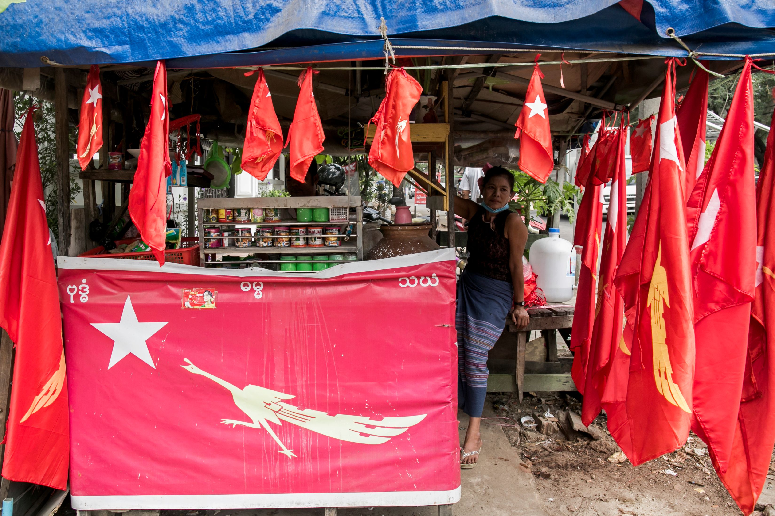 Seorang pendukung NLD memasang bendera partai itu di tokonya di Yangon, Myanmar.