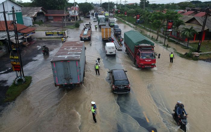 Foto udara kendaraan melintas digenangan banjir di jalur Pantura Kedungkelor, Kabupaten Tegal, Jawa Tengah, Kamis (14/1/2021).  