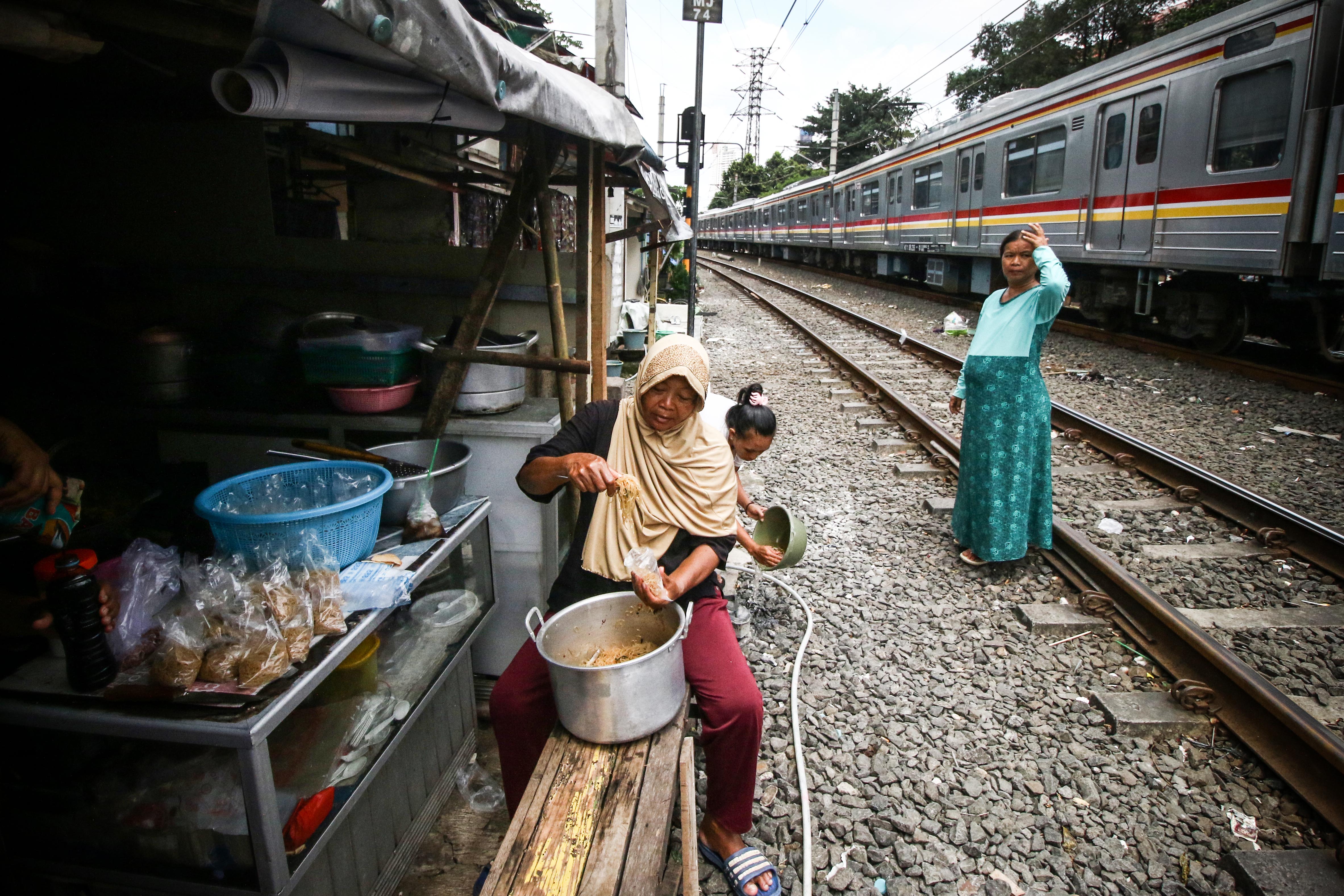 Warga berjualan di depan rumah semi permanen yang berlokasi di pinggir rel Pejompongan, Jakarta.