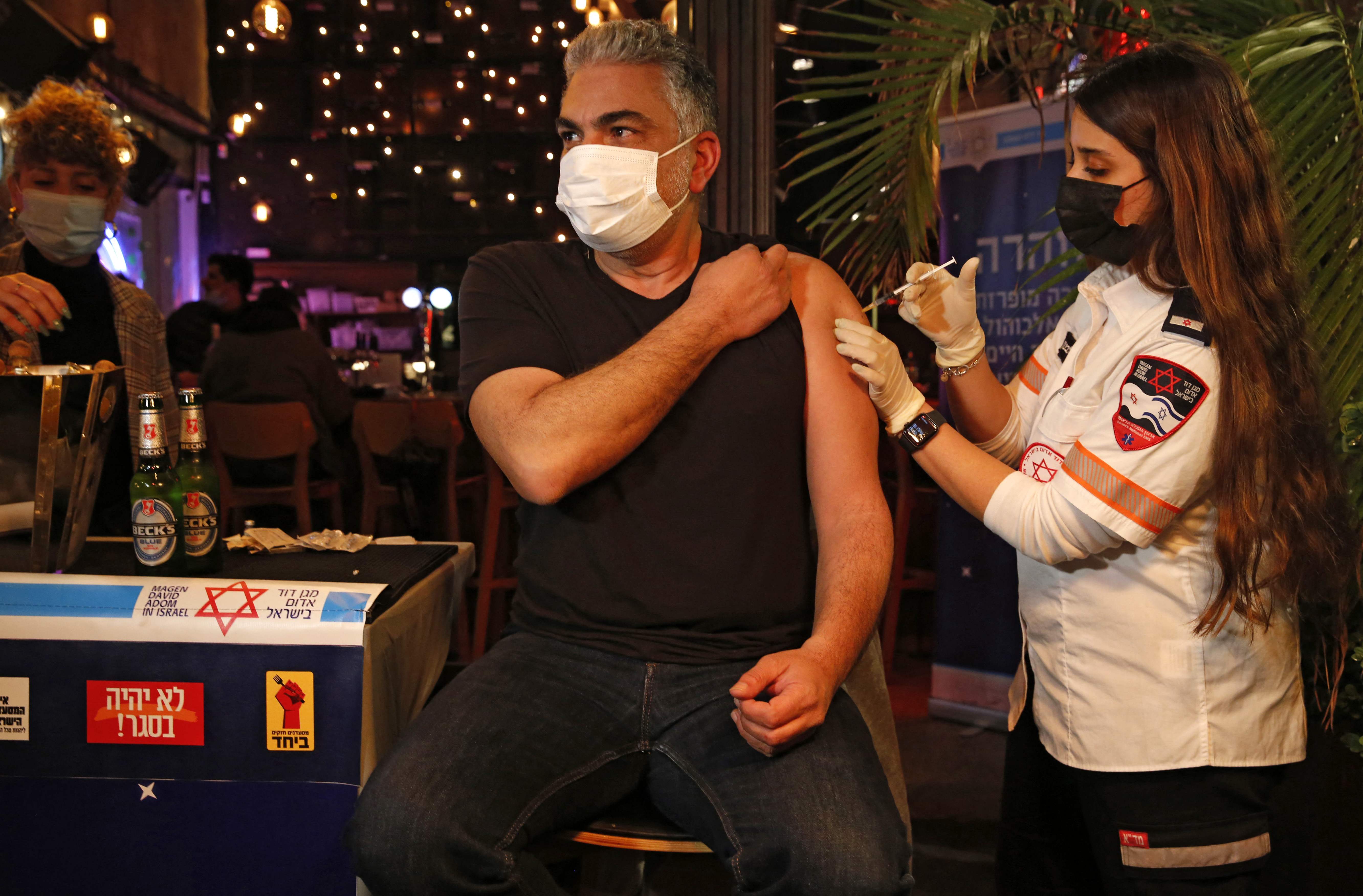 Petugas kesehatan memberikan vaksin covid-19 kepada warga di sebuah bar di Tel Aviv, Israel, Kamis (18/2/2021).