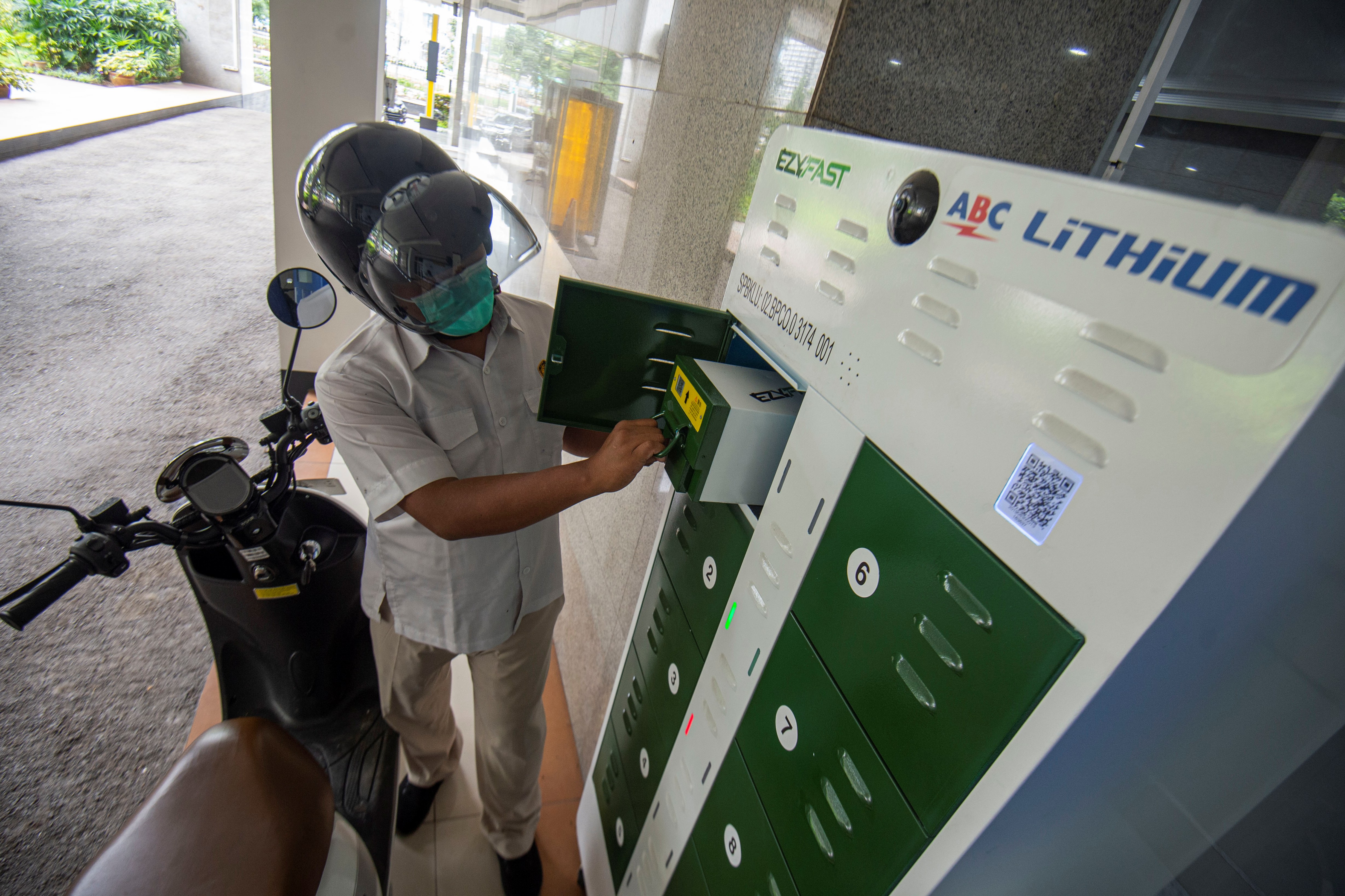 Karyawan mengganti baterai sepeda motor listrik di Stasiun Penukaran Baterai Kendaraan Listrik Umum (SPBKLU), Jakarta.