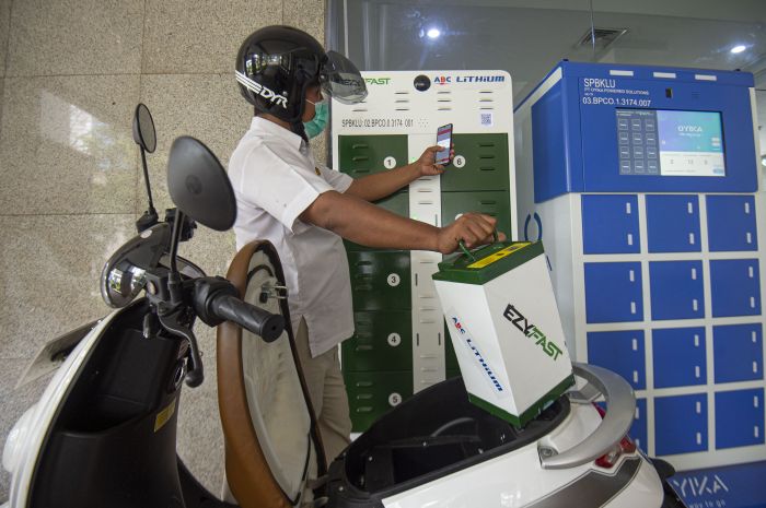 Karyawan mengganti baterai sepeda motor listrik di Stasiun Penukaran Baterai Kendaraan Listrik Umum (SPBKLU) di Jakarta.  