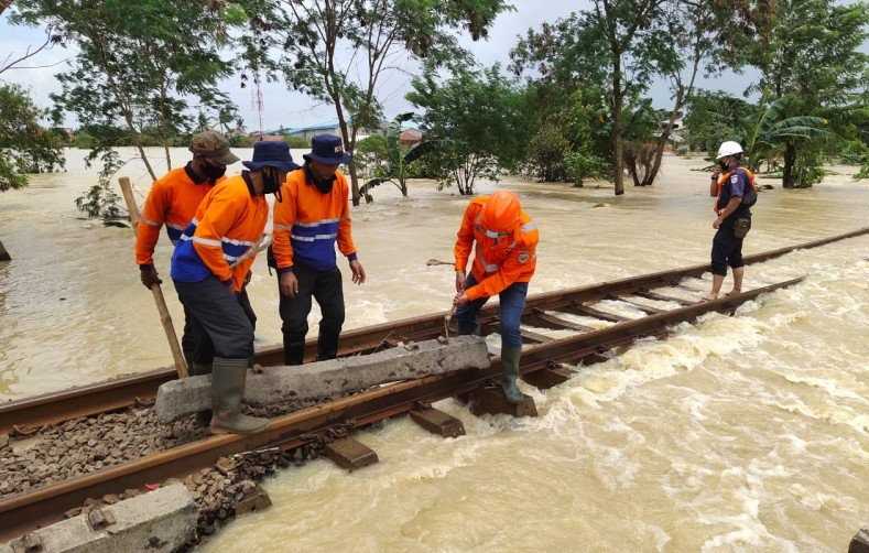 Petugas KAI melakukan perbaikan jalur rel yang rusak akibat banjir. 