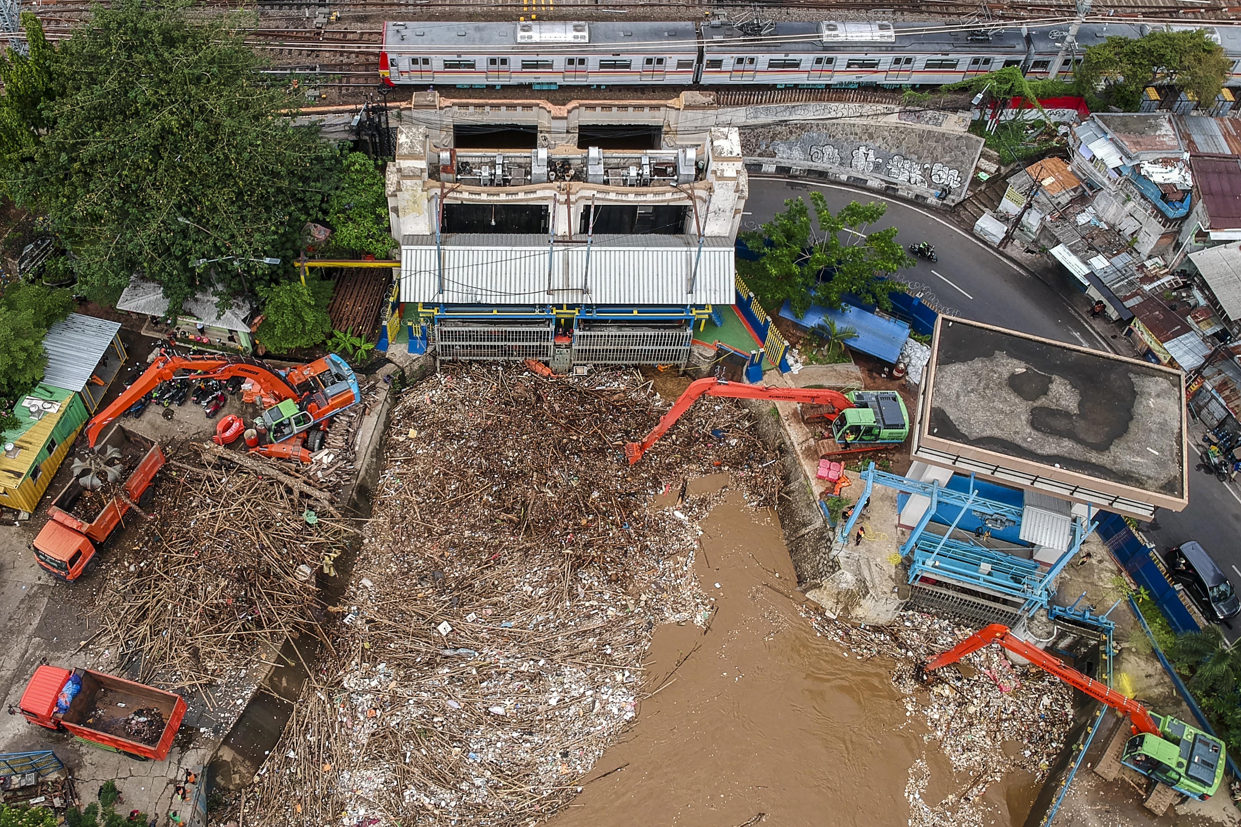 Petugas Dinas Kebersihan DKI Jakarta menggunakan alat berat membersihkan sampah di pintu air Manggarai, Jakarta, Selasa (22/9/2020)