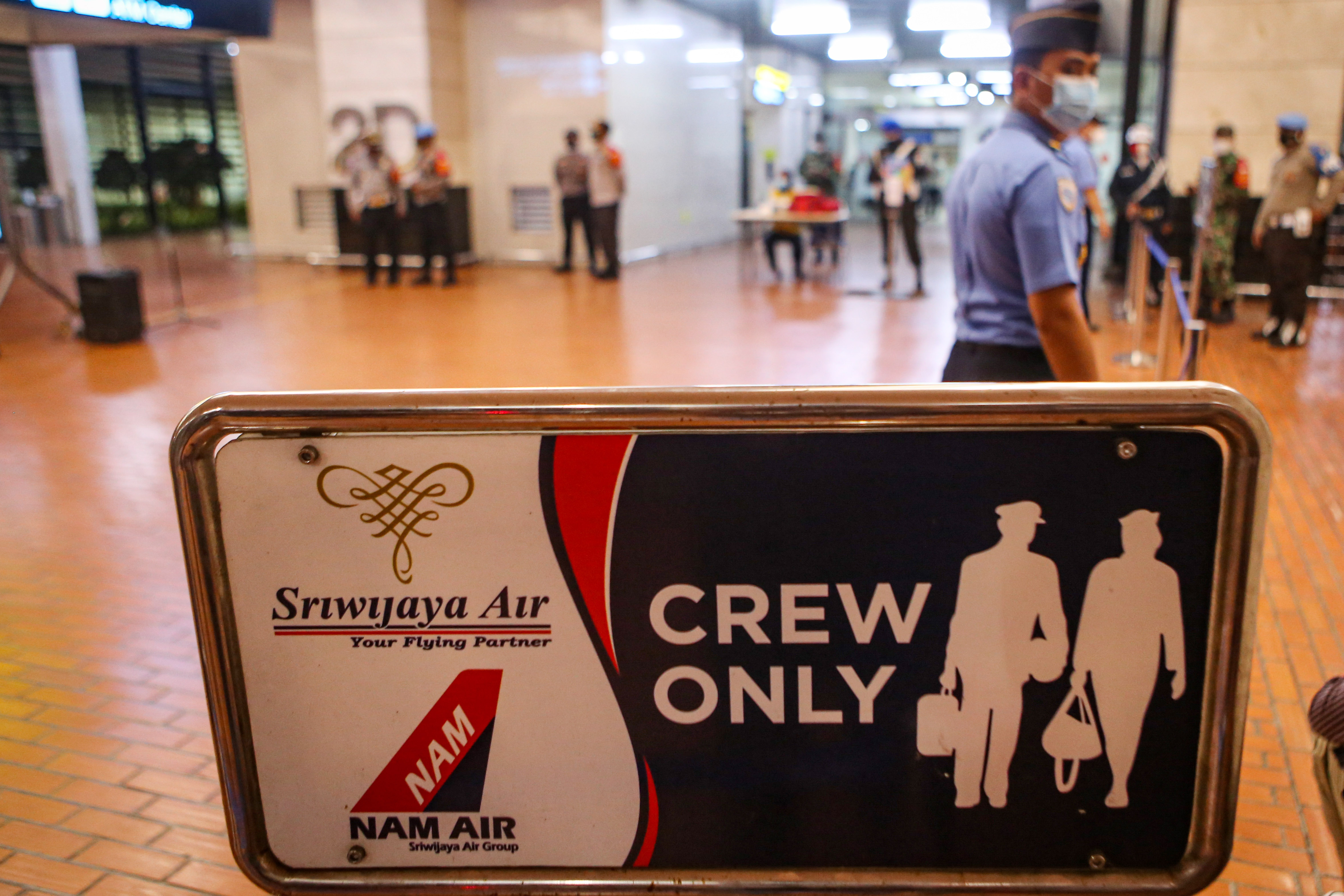 Petugas melintasi logo perusahaan angkutan udara Sriwijaya dan NAM Air di Bandara Soekarno-Hatta, Tangerang, Banten.