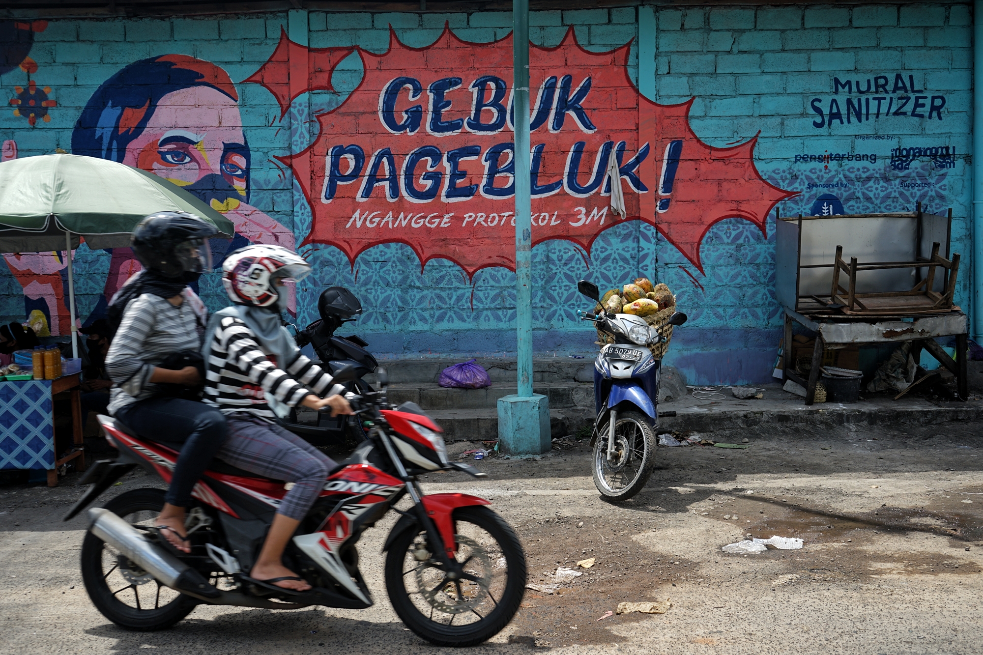 Warga DIY melintas di depan mural sosialisasi bahaya Covid-19.