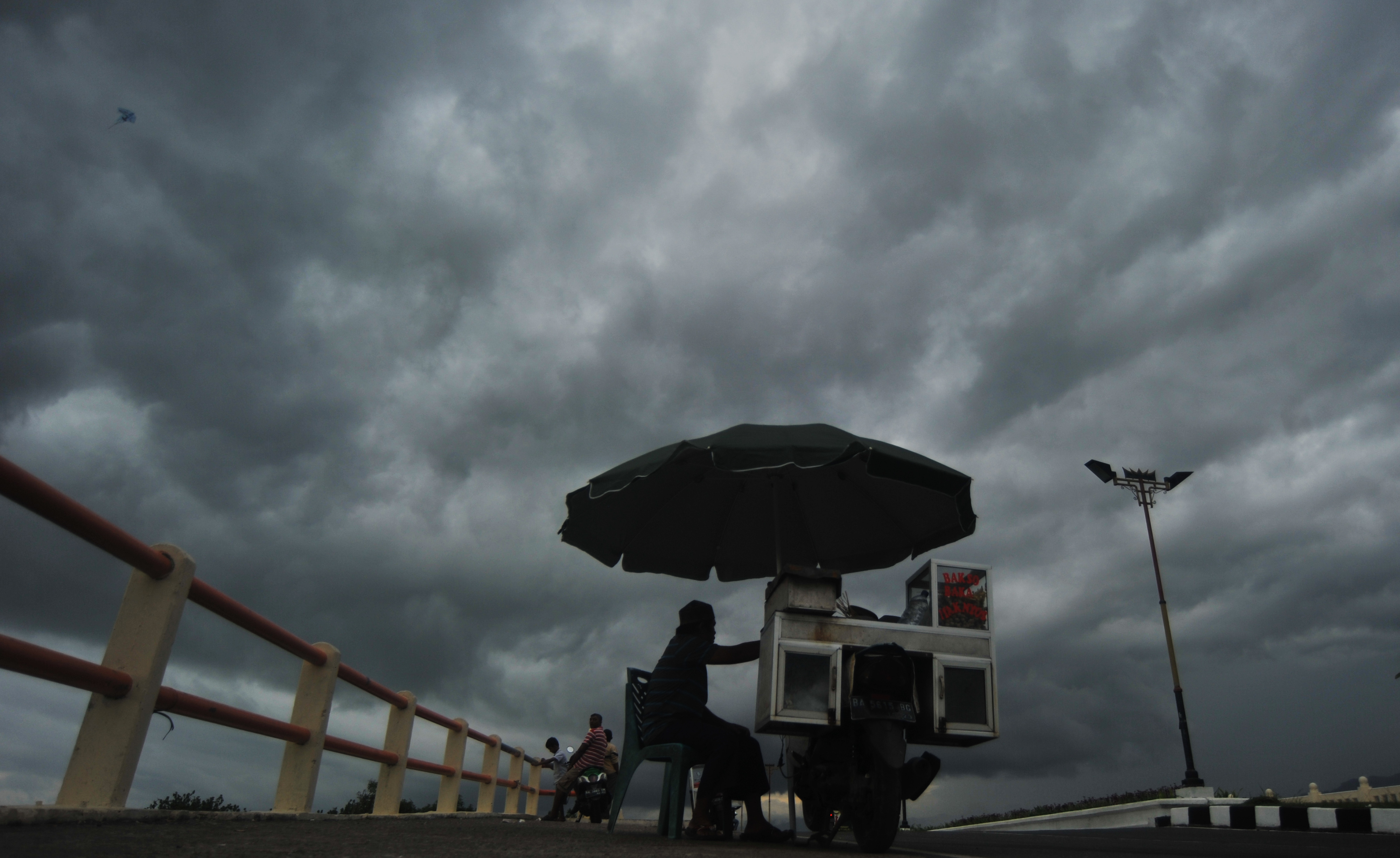 Pedagang buah berjualan saat awan menyelimuti kawasan Pantai Padang, Sumatera Barat, Selasa (2/2).