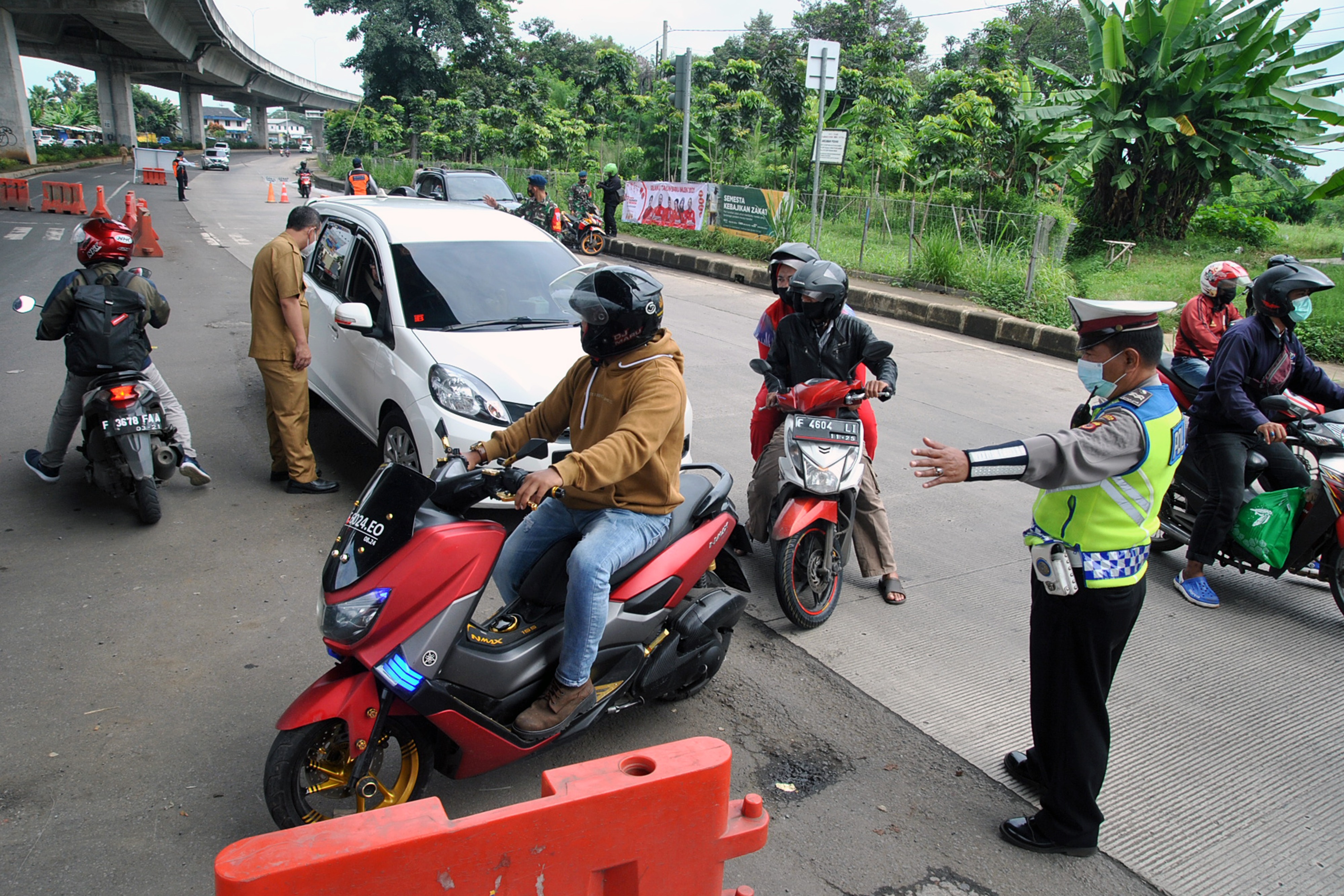 Anggota Polresta Bogor Kota mengarahkan kendaraan bermotor untuk berputar balik saat pemberlakuan aturan ganjil-genap di Kota Bogor.