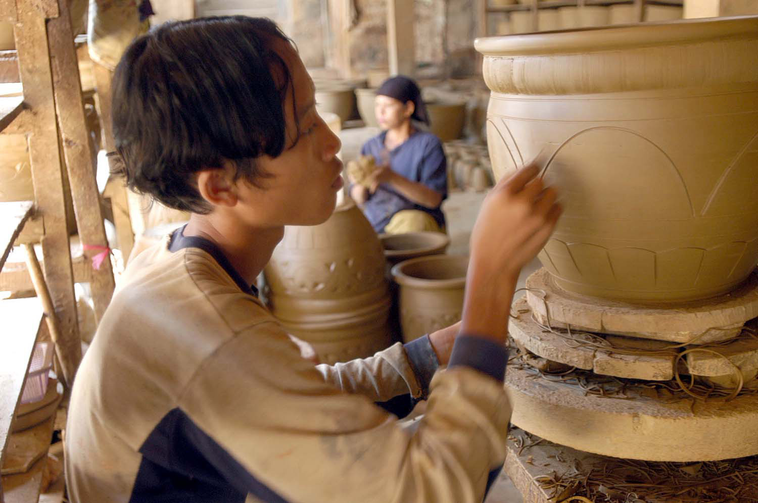 Seorang pekerja tengah memberikan sentuhan terakhir dari pembuatan sebuah pot bunga di Plered