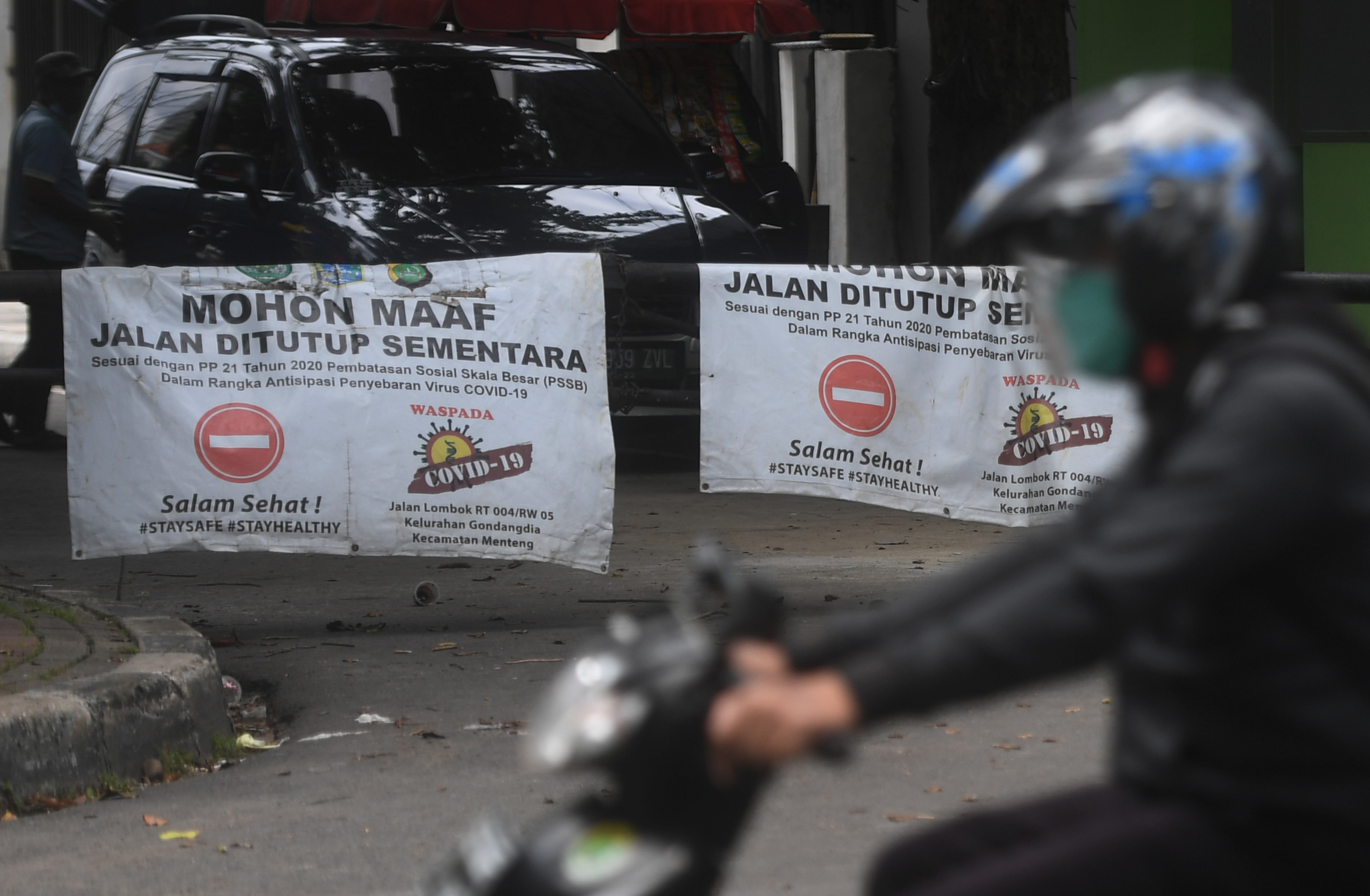 Pesepeda motor melewati pagar karantina wilayah saat pemberlakuan PPKM skala mikro di Jakarta, Selasa (9/2).