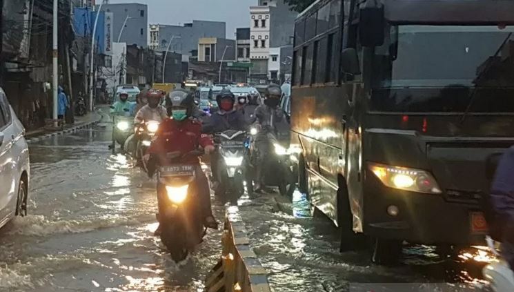 Pengendara di Jalan Jatinegara Barat, terjebak kemacetan akibat badan jalan terendam luapan Sungai Ciliwung, Senin (8/2).