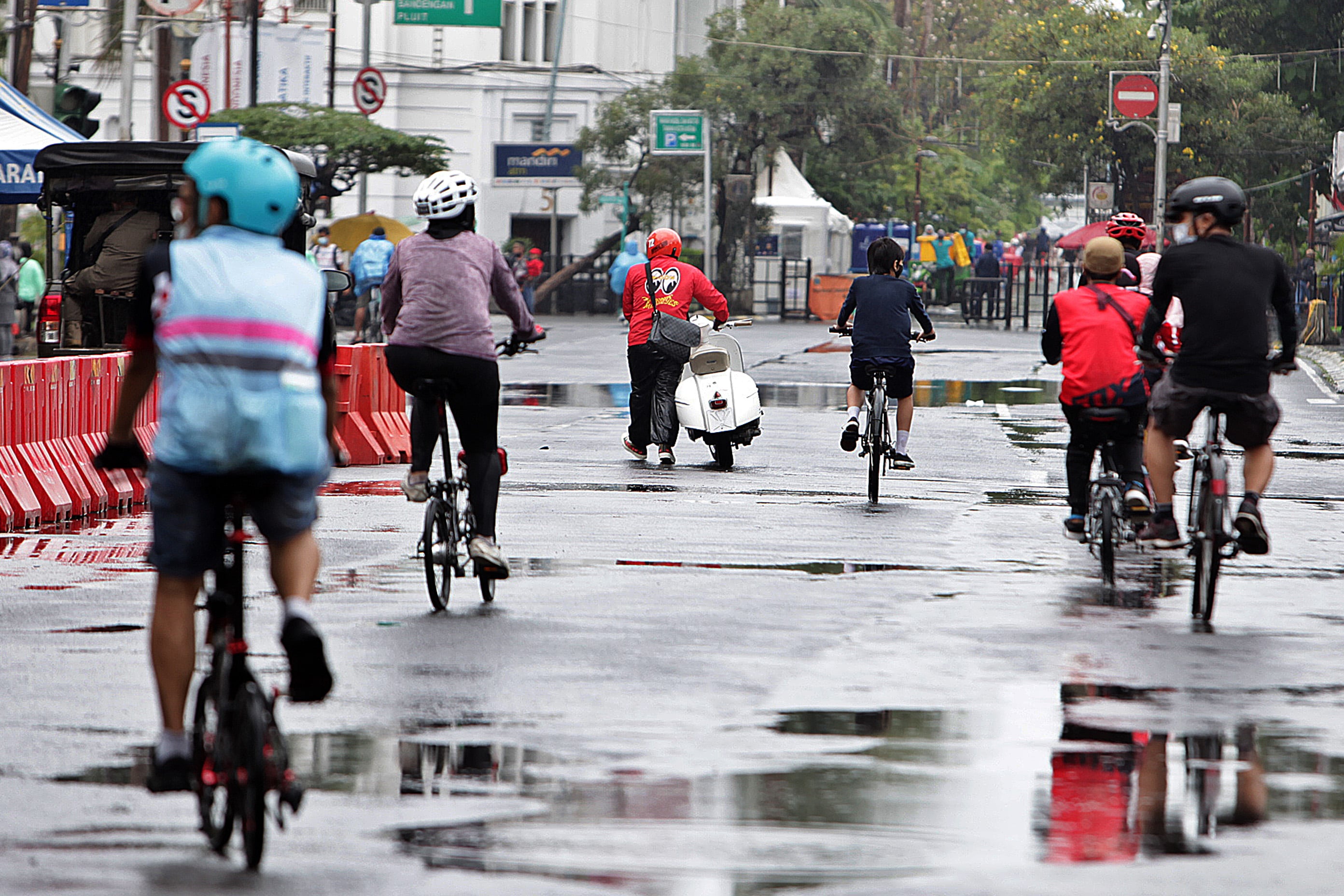 Pengendara sepeda motor mendorong kendaraannya agar bisa melintasi kawasan Kota Tua di Jakarta.