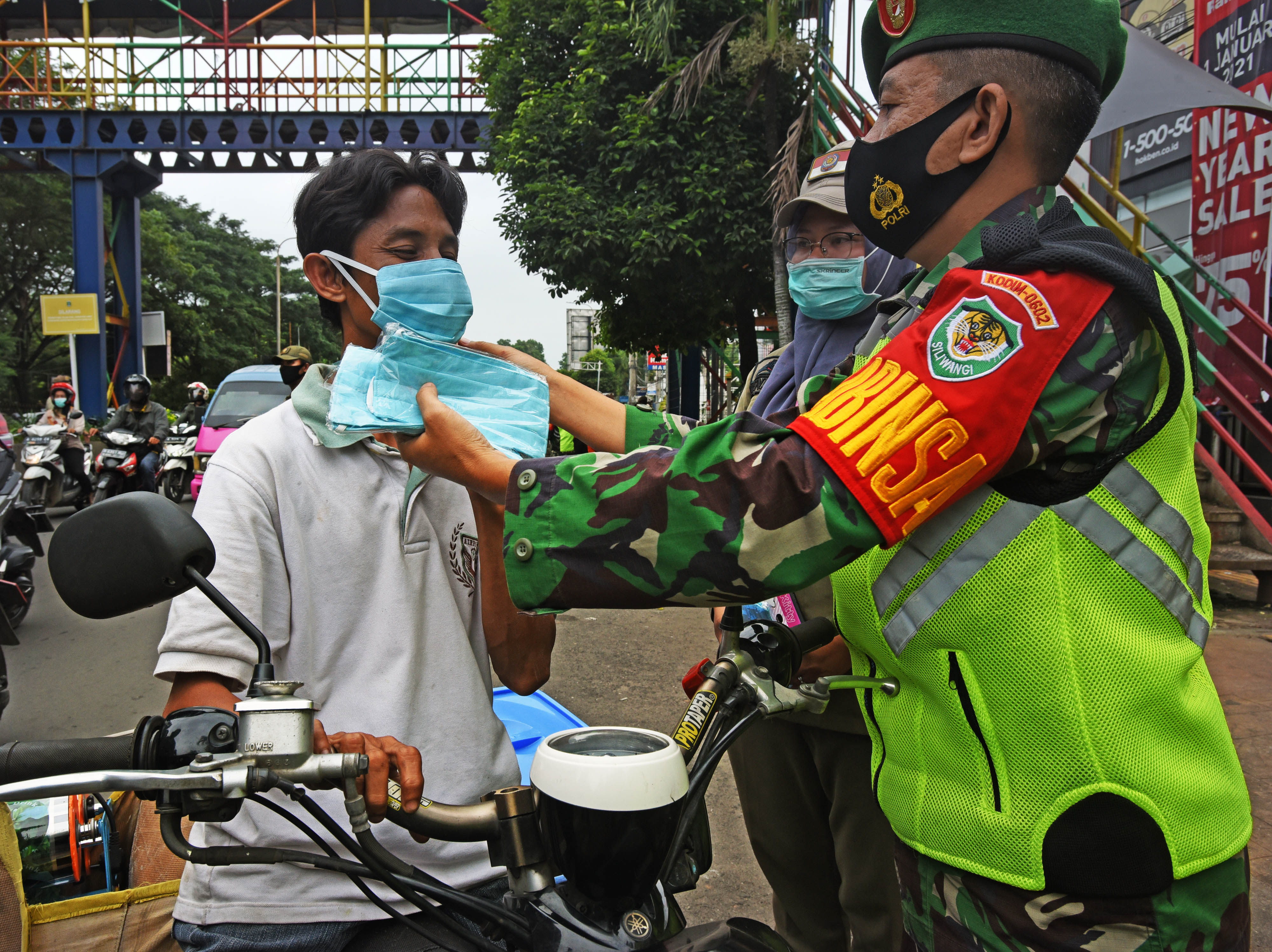 Petugas memberikan masker saat razia protokol kesehatan tingkat kelurahan