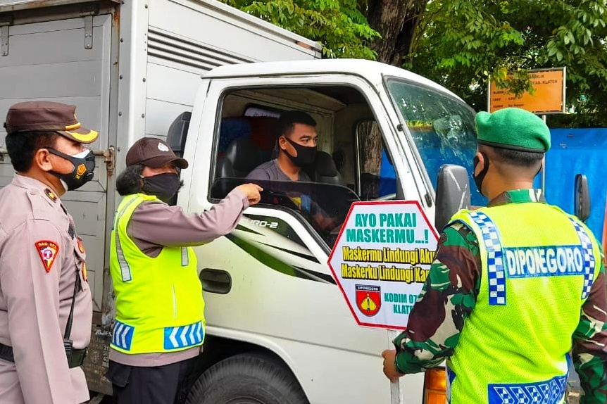 Petugas gabungan Polres dan Kodim Klaten membagikan masker kepada pengemudi mobil boks.