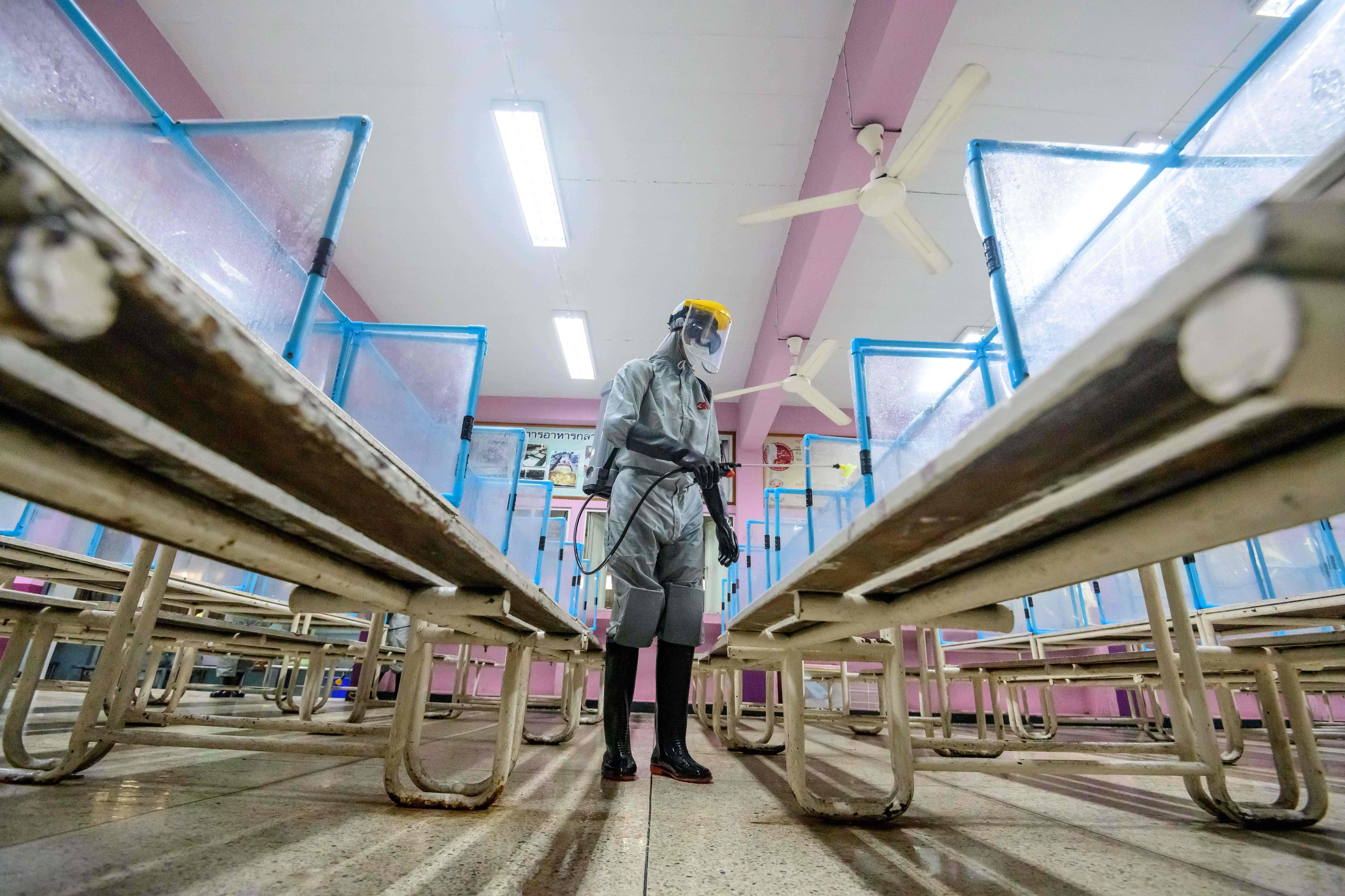 Petugas melakukan penyemprotan disinfektan di area kantin sekolah di Bangkok, Thailand.
